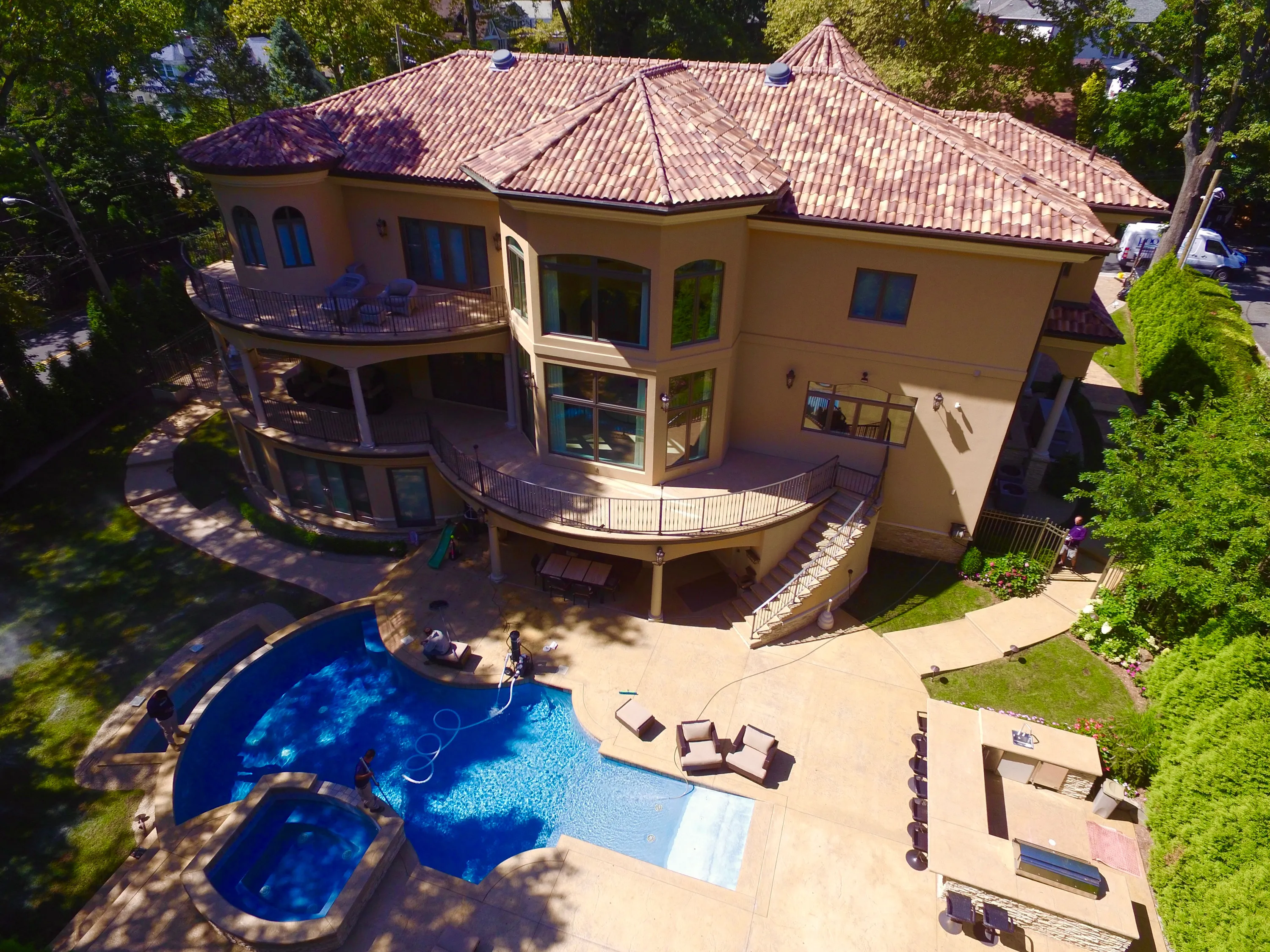 Aerial view of a residence, curved pool, and wooded grounds in New York.