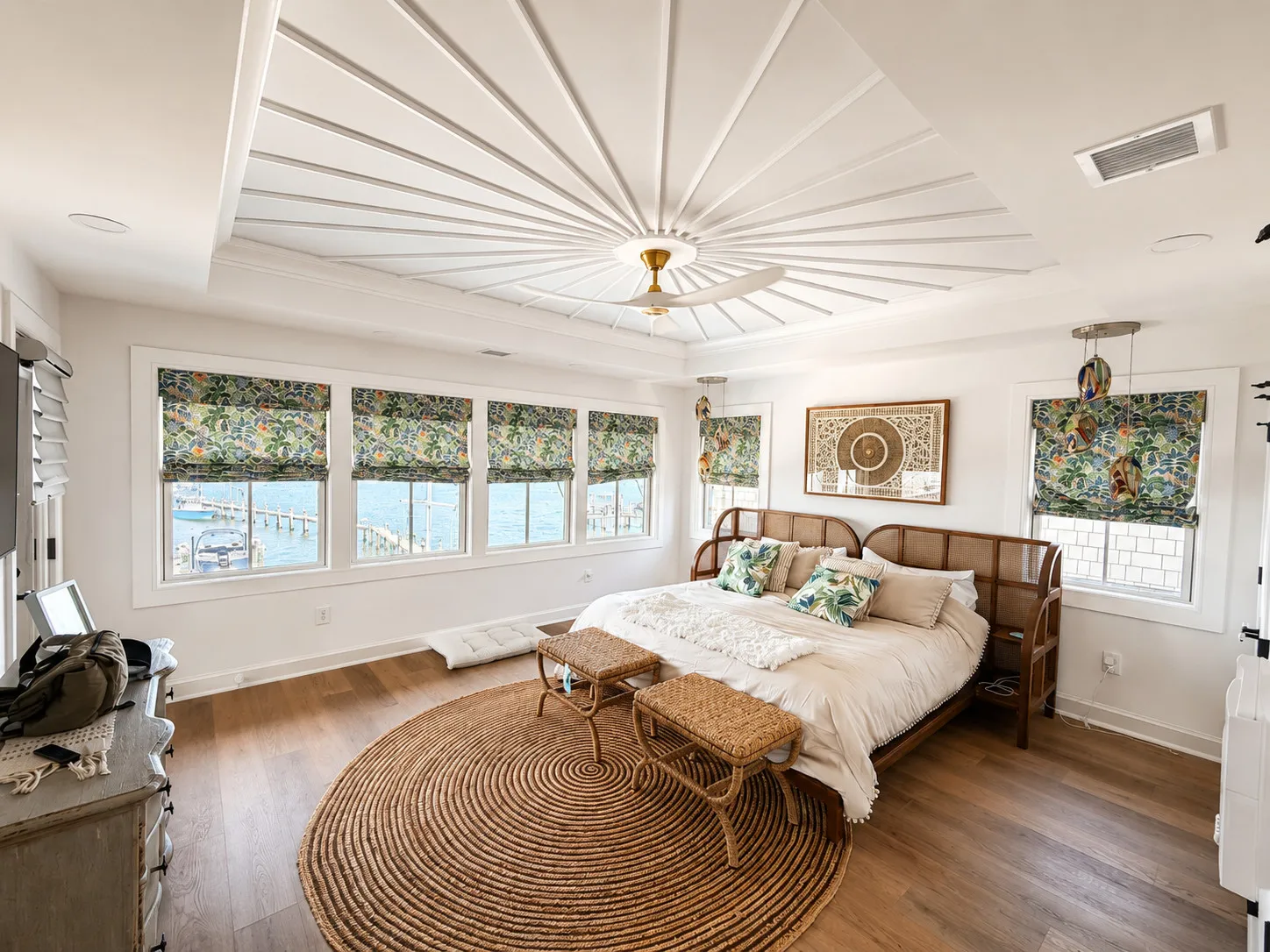 Coastal bedroom with a radiating ceiling detail and broad windows.