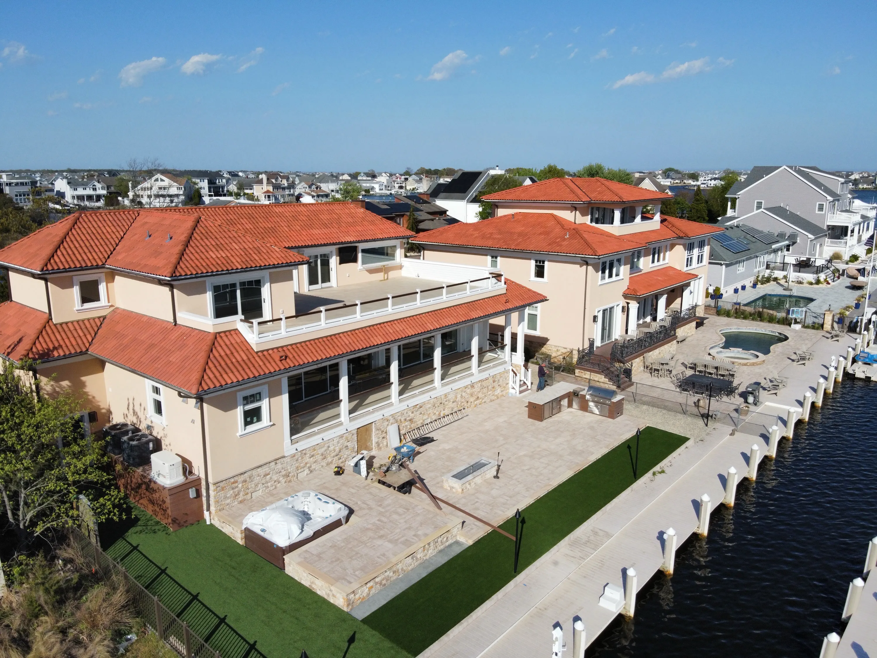 Aerial waterfront view of a residence with deep terraces and a terracotta roof.