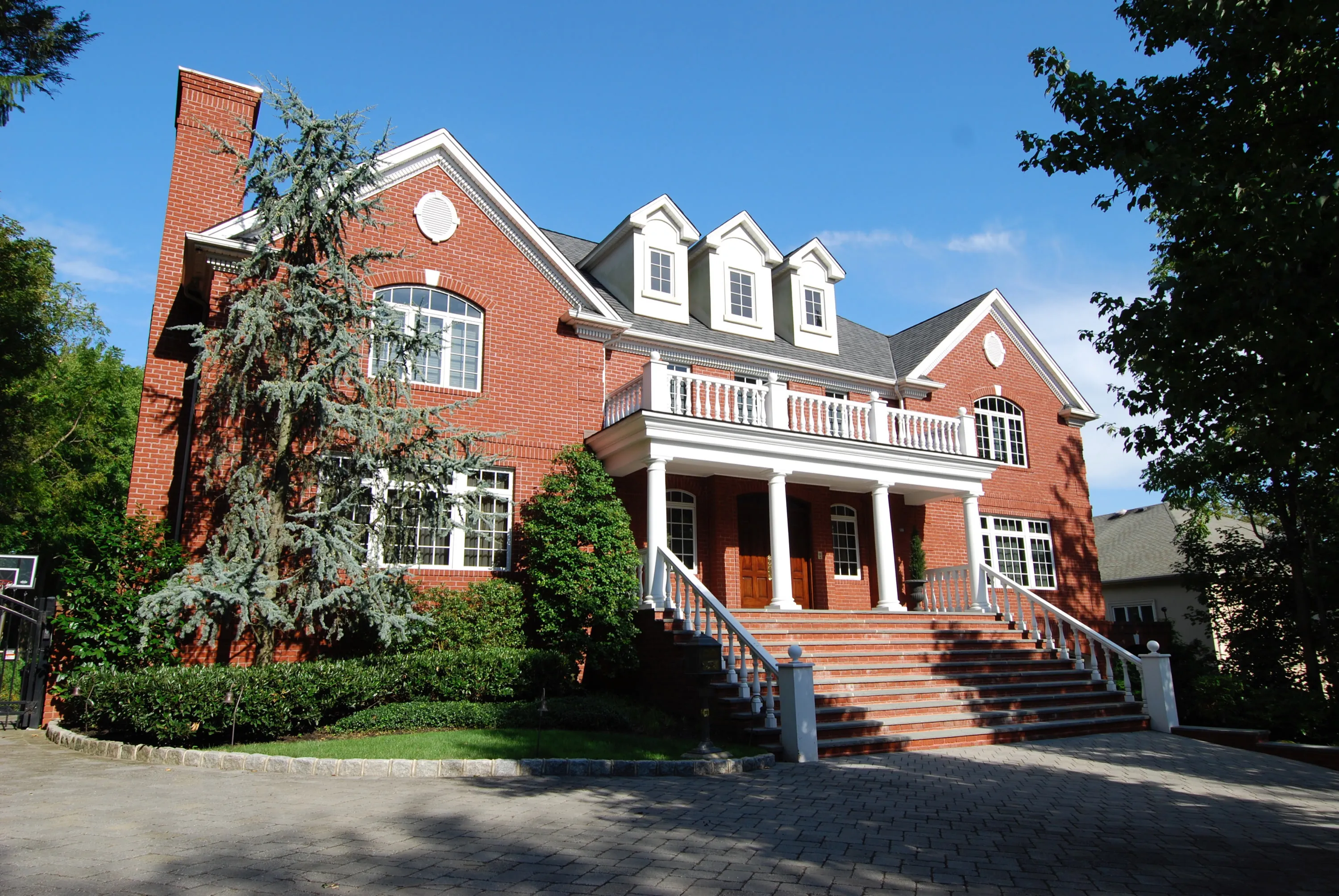 Angled front view of the brick residence framed by mature trees.