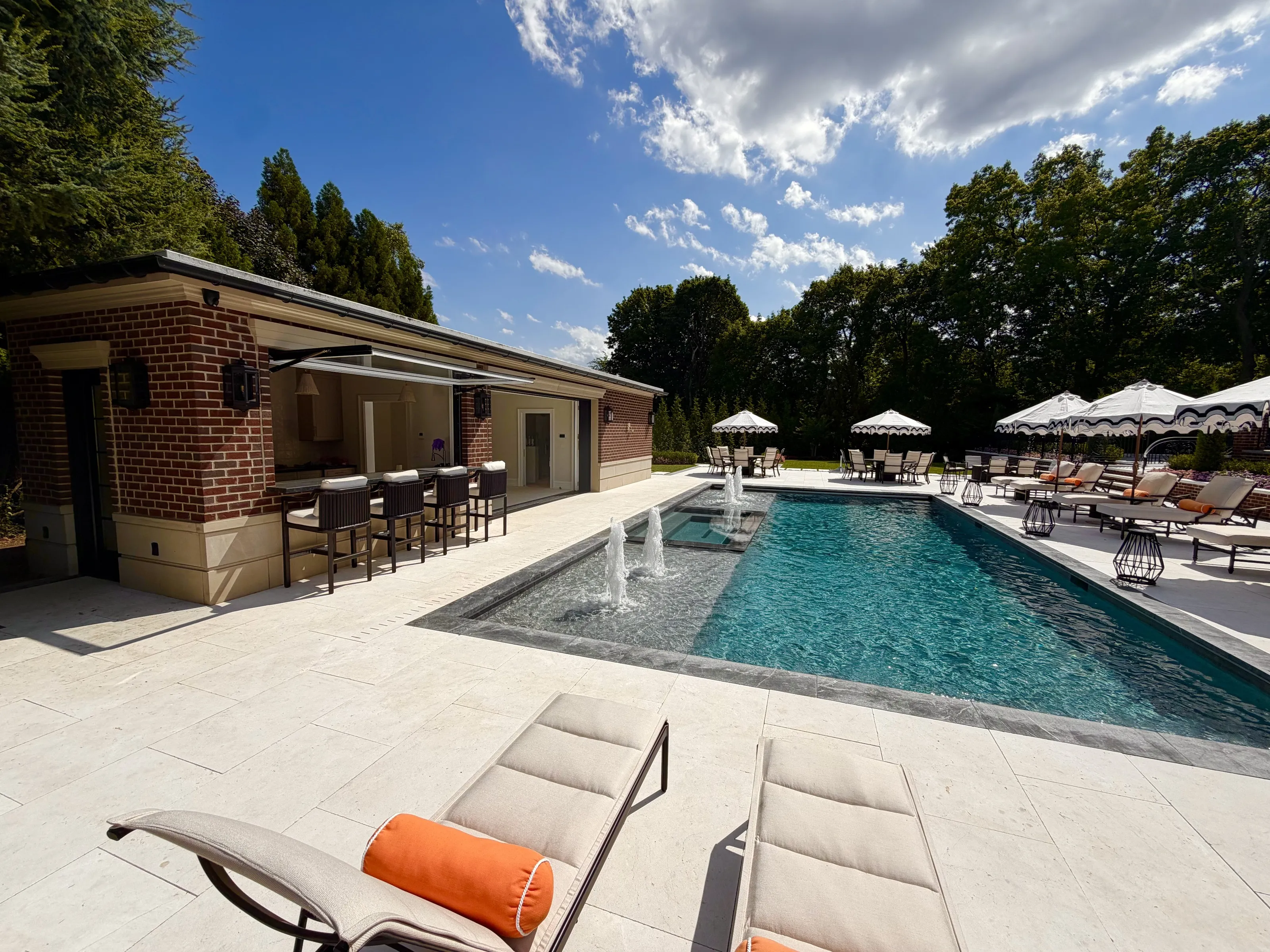 Wide pool terrace with a pavilion, dining areas, and shaded seating.