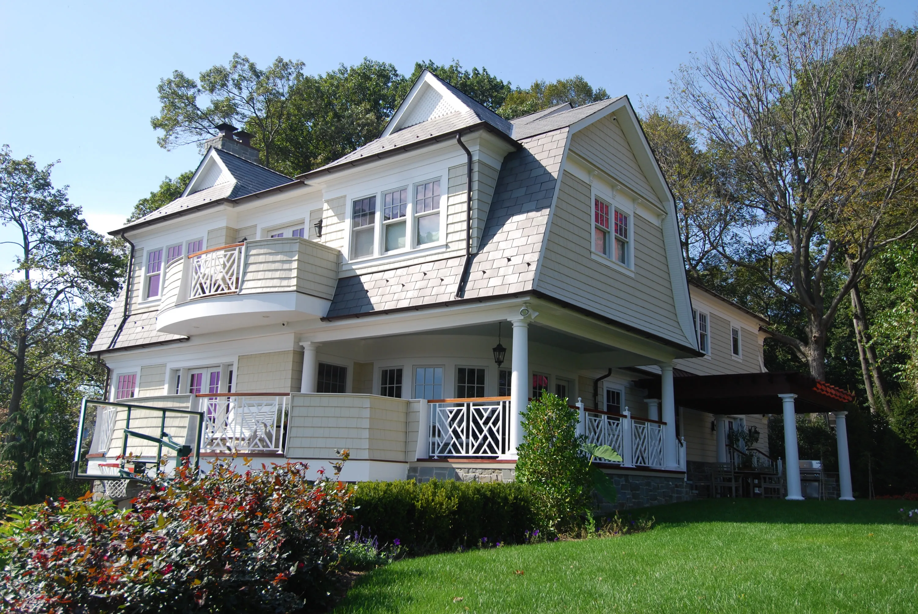Garden view of a shingle and stone residence with wraparound porches and balconies.