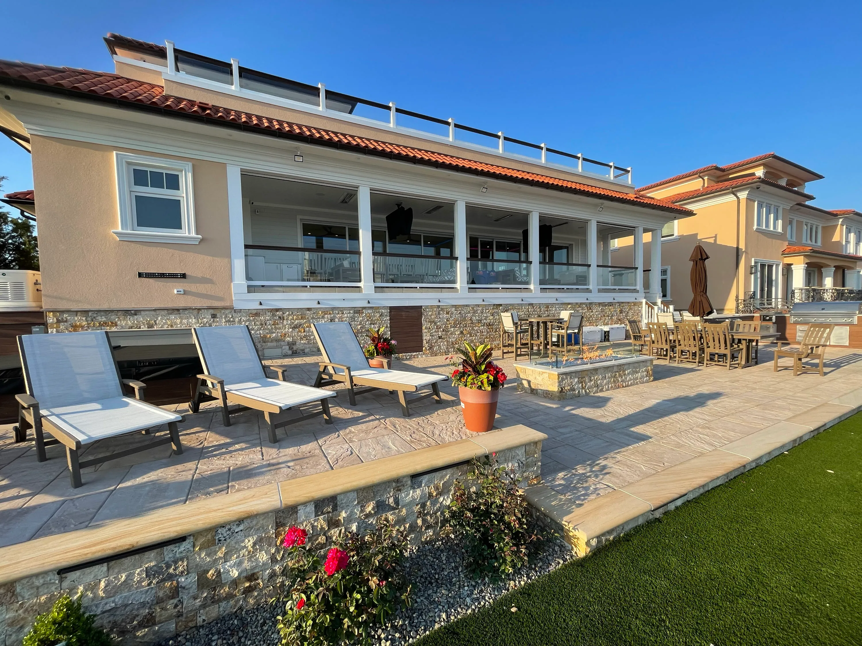 Rear terrace with stone paving, outdoor seating, and broad waterfront views.