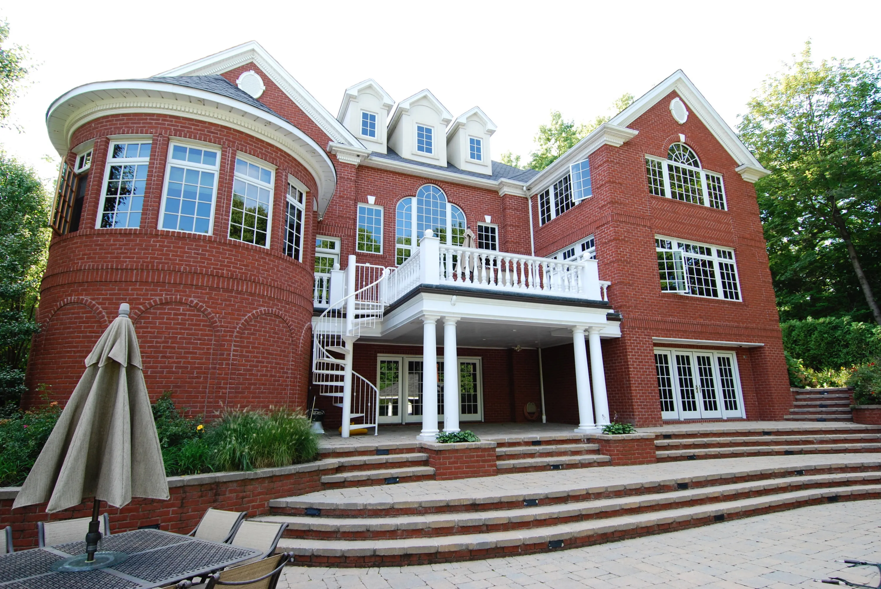 Rear elevation of the brick residence with curved windows and broad masonry steps.