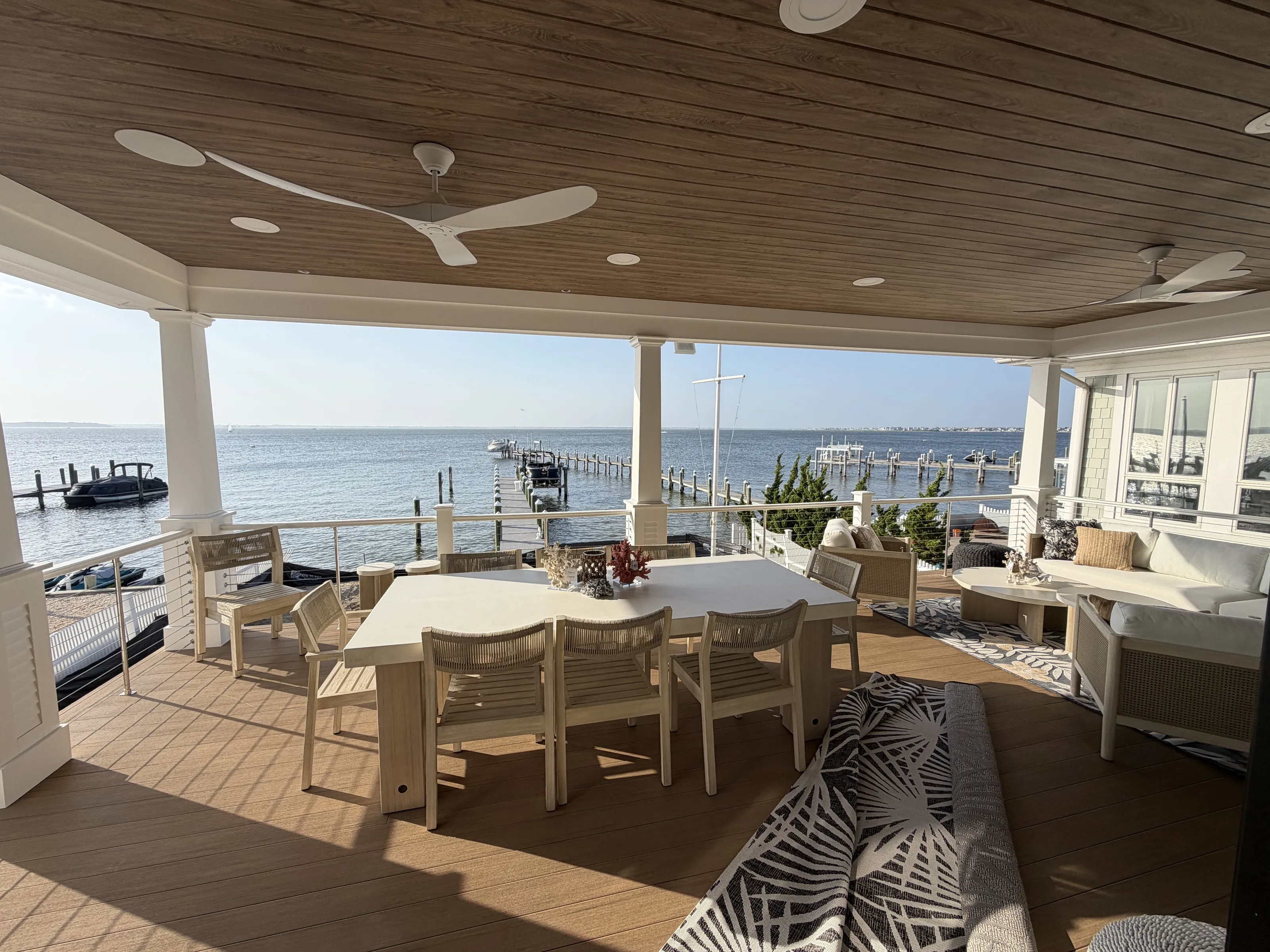 Covered waterfront deck with dining and seating areas overlooking the bay.