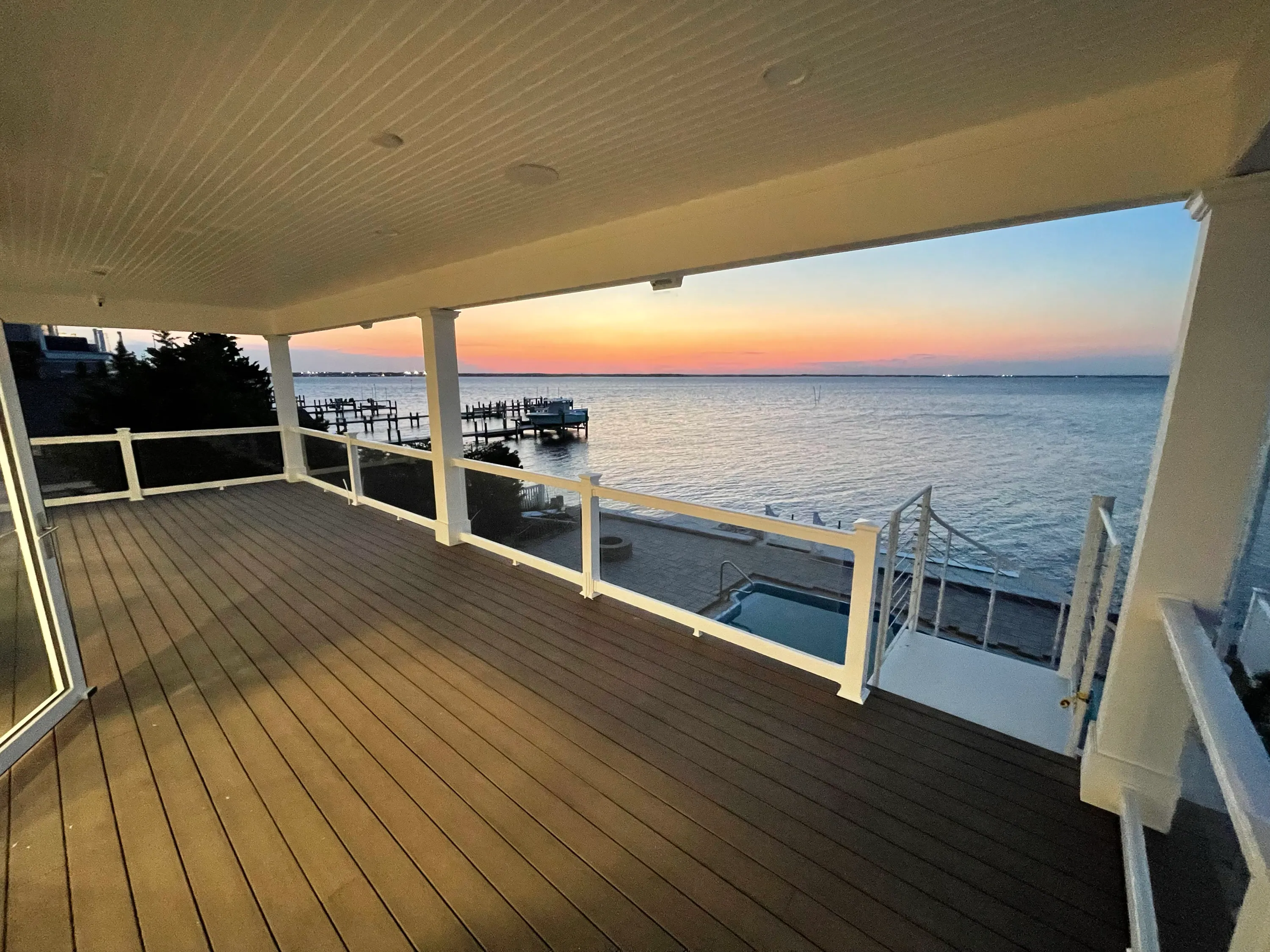 Covered waterfront porch opening toward the bay at sunset.