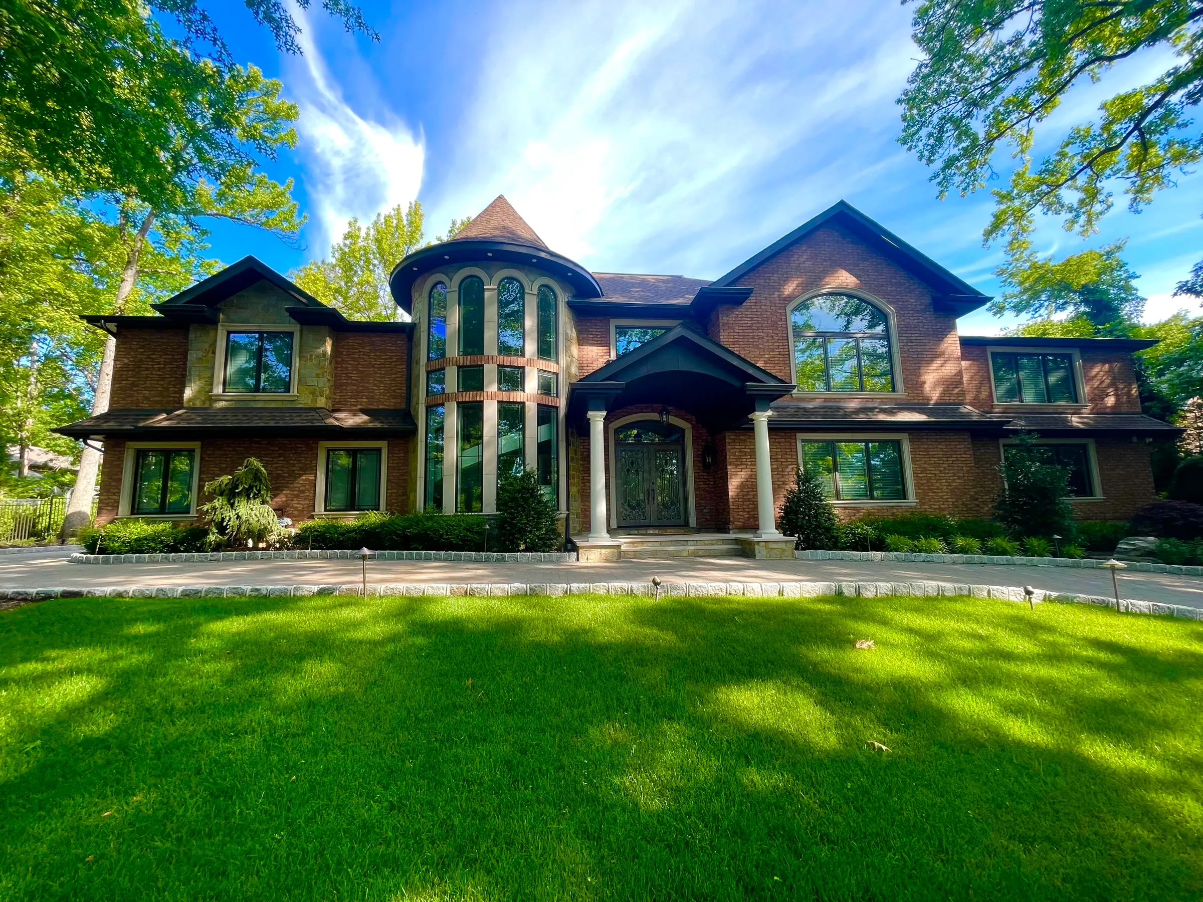 Broad completed residence with substantial masonry and landscaped grounds.