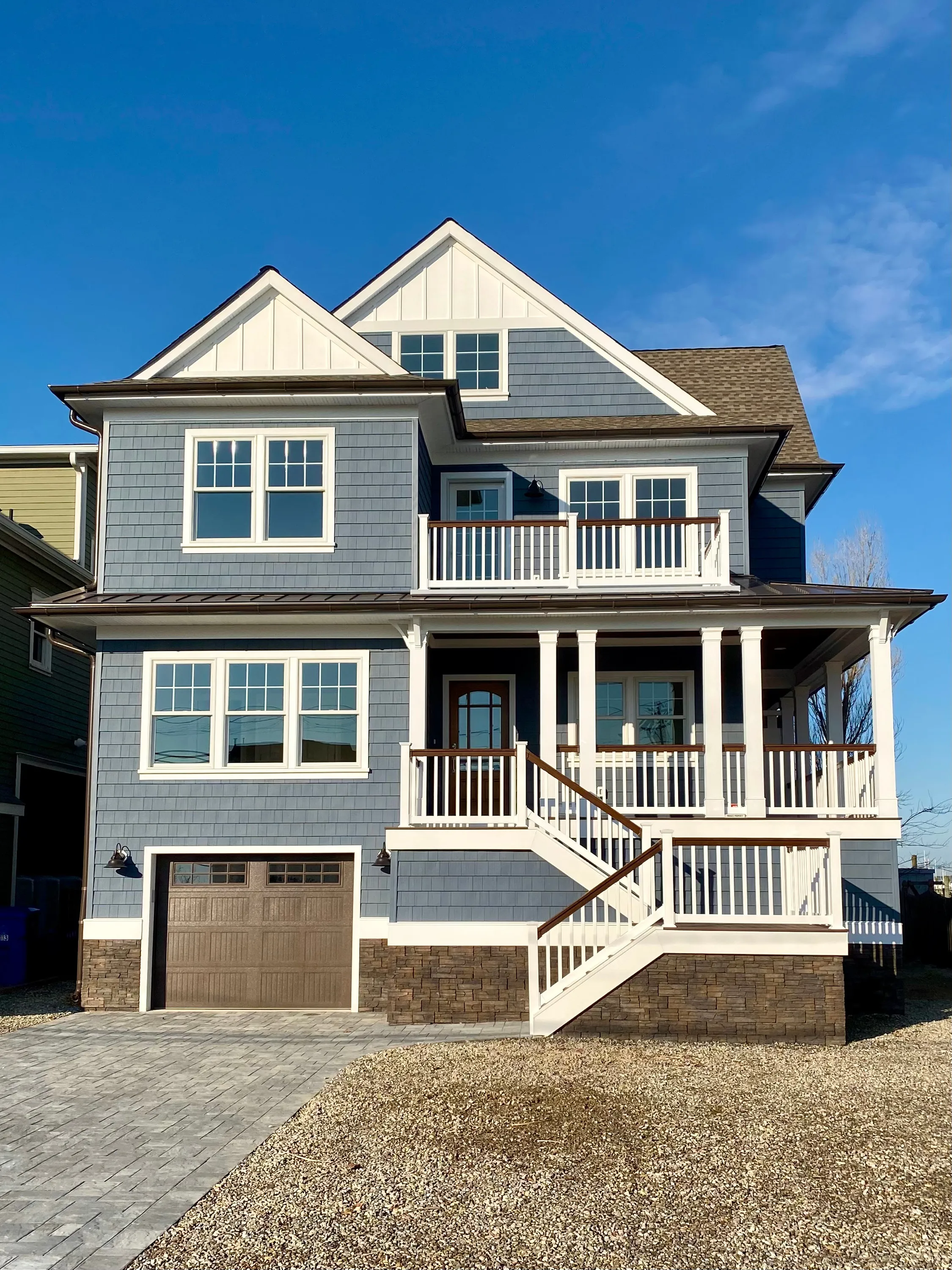 Gray coastal residence with a full-width porch in New Jersey.