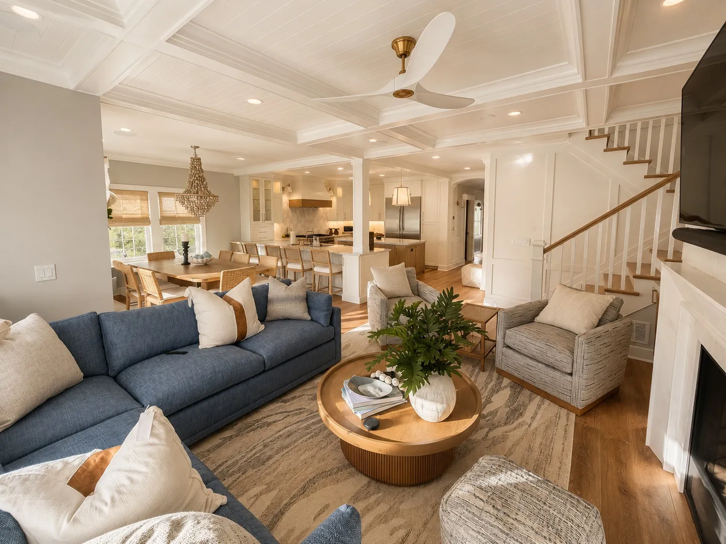 Open living, dining, and kitchen space with detailed ceiling trim and pale millwork.