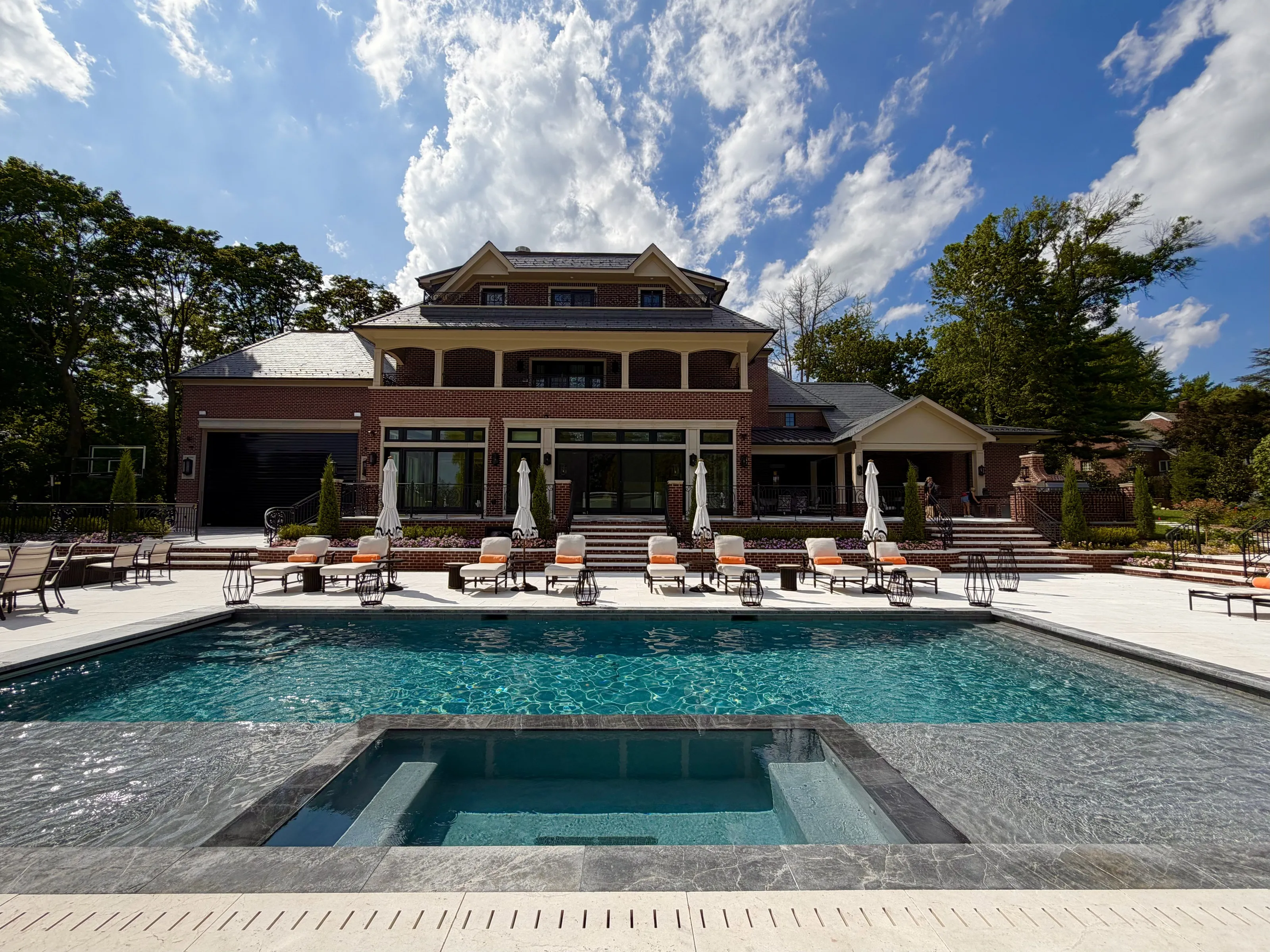 Large brick residence facing a centered pool and integrated spa.
