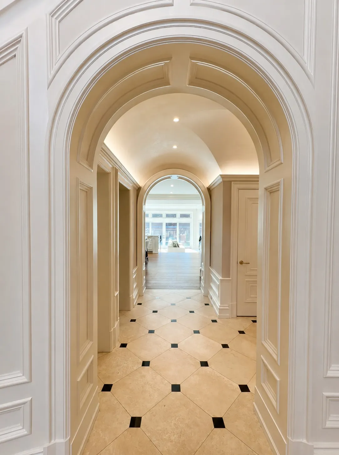 Long arched gallery with paneled walls and patterned stone flooring.