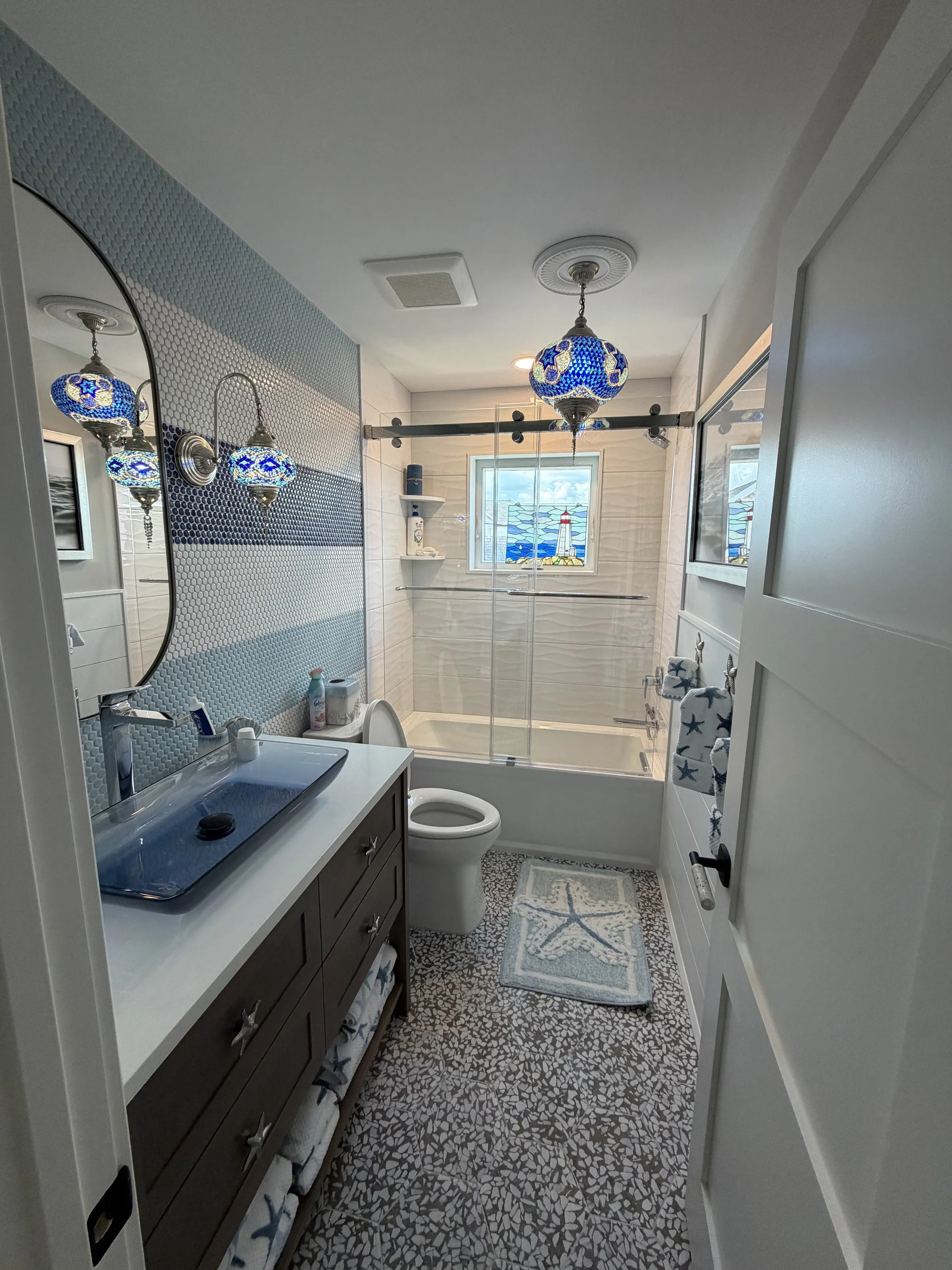 Bathroom with blue tile, brass fittings, and a glass shower enclosure.