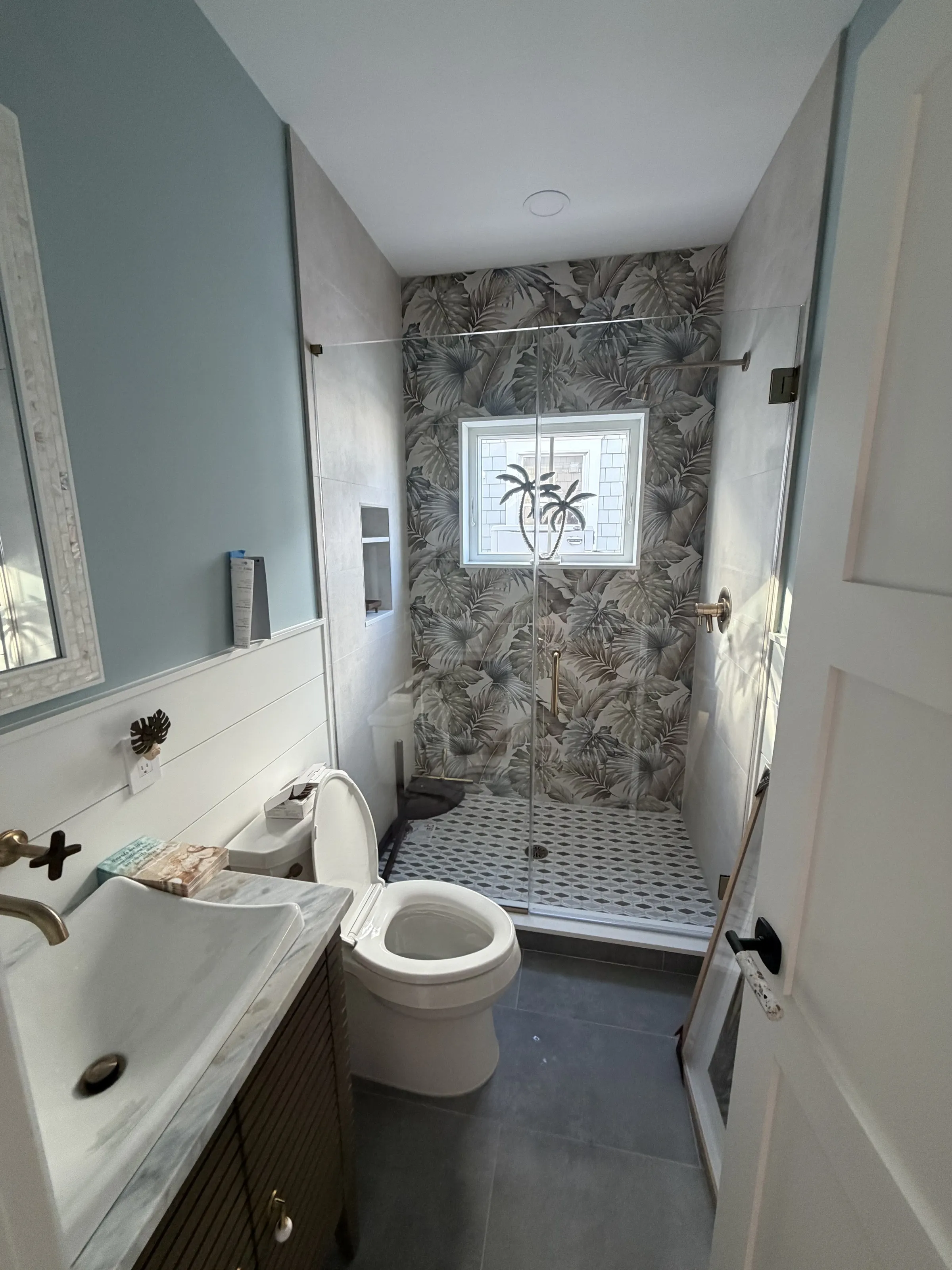 Bathroom with a stone shower wall and dark vanity.