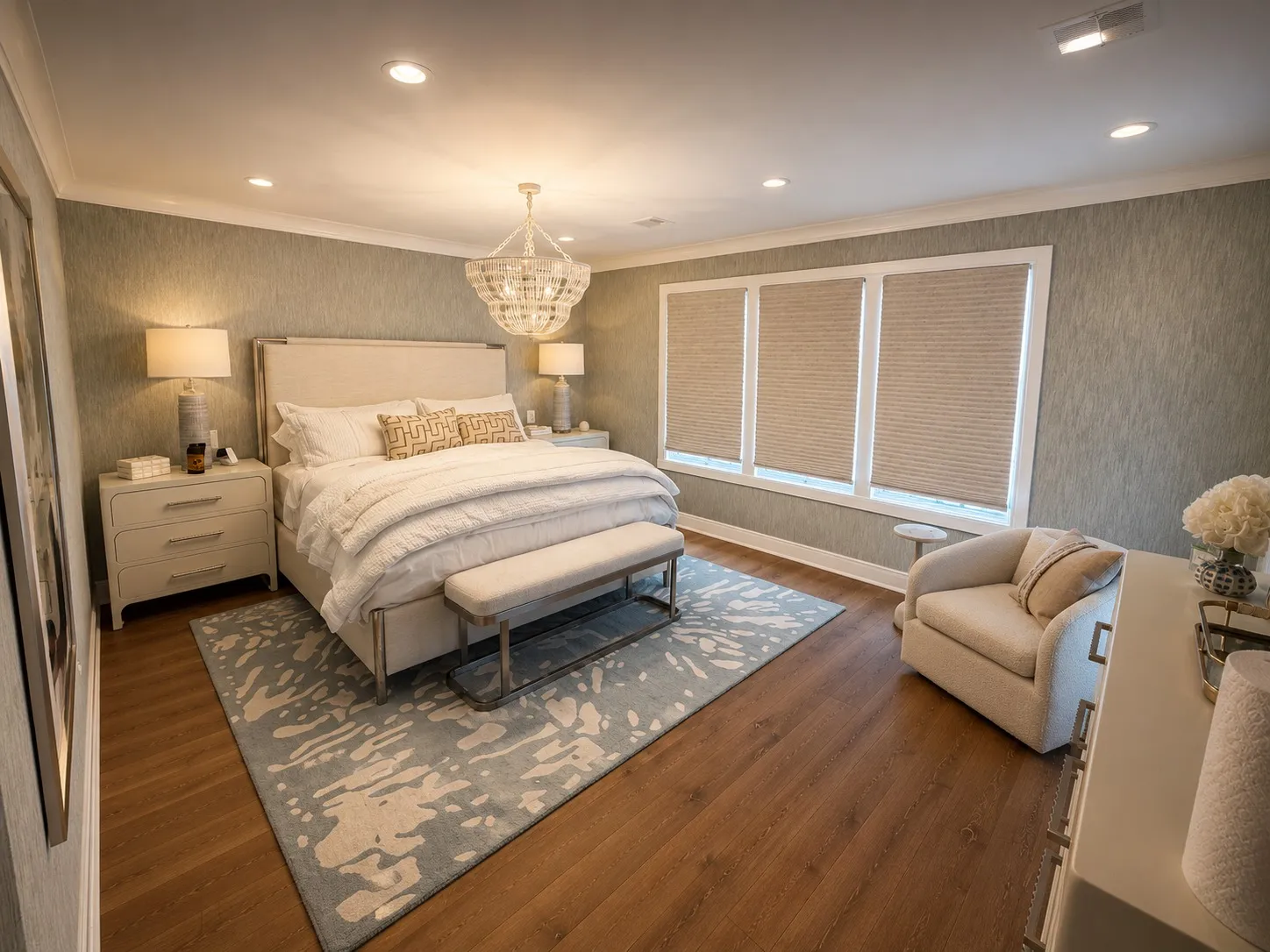 Primary bedroom with a chandelier and layered neutral finishes.