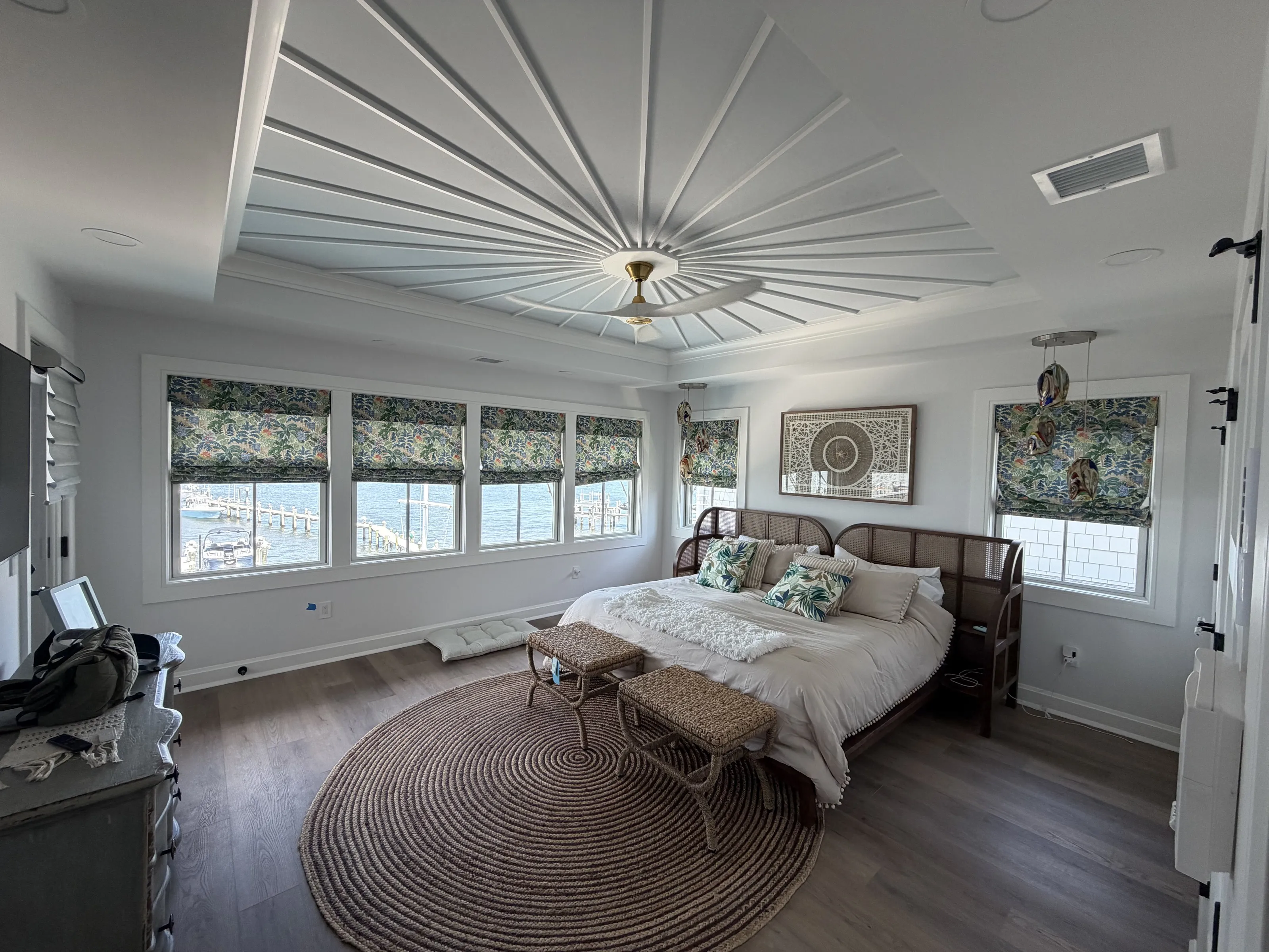 Bedroom with a radiating ceiling detail and broad windows.