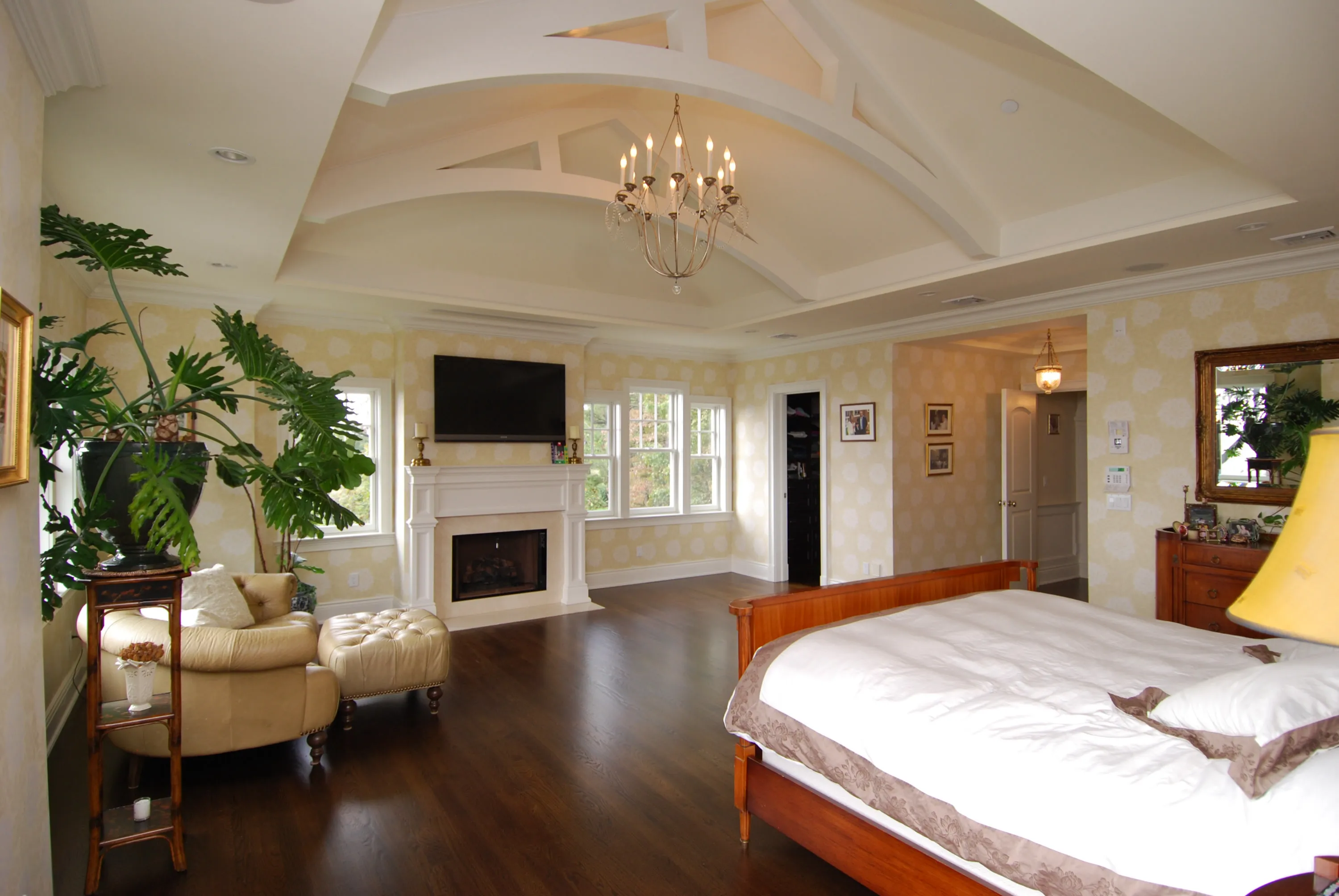 Bedroom with a coffered ceiling, fireplace, and dark wood flooring.