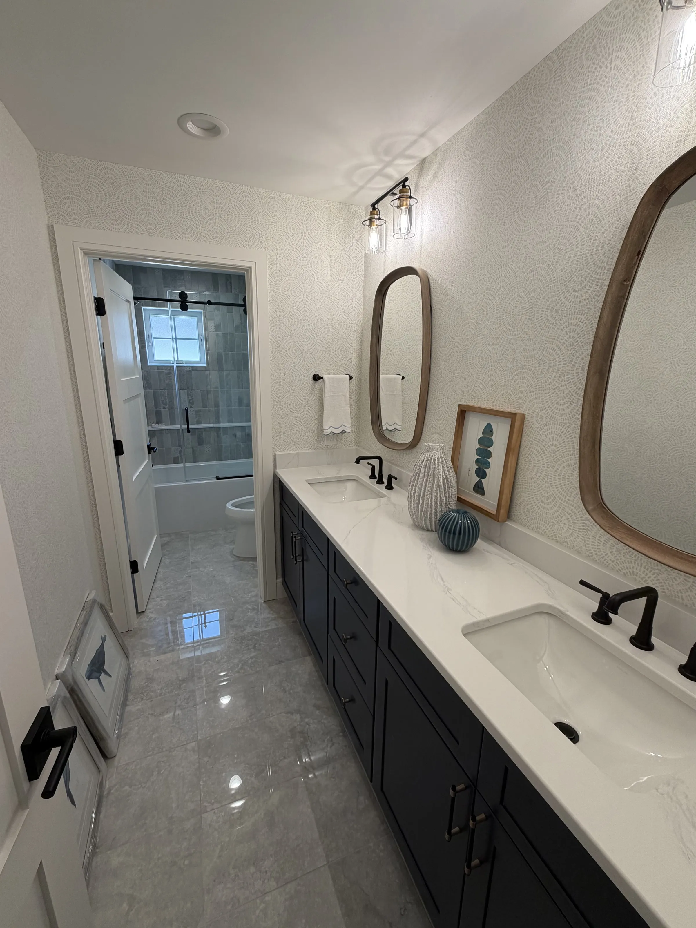Long double vanity with dark cabinetry and a pale stone counter.