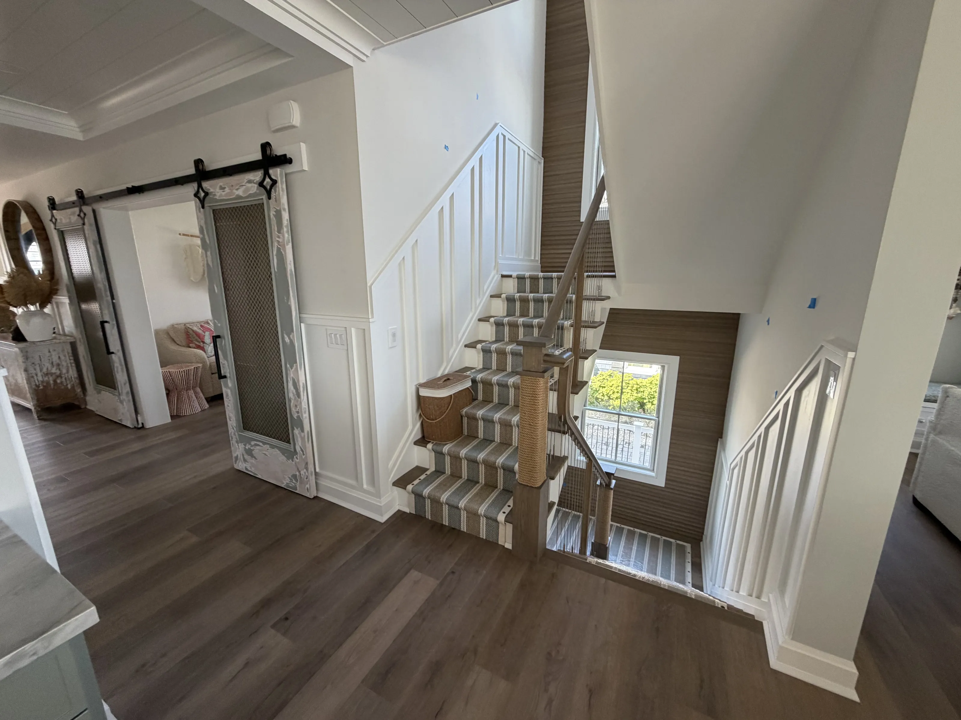 Open entry and stair connection with paneled walls and wood flooring.