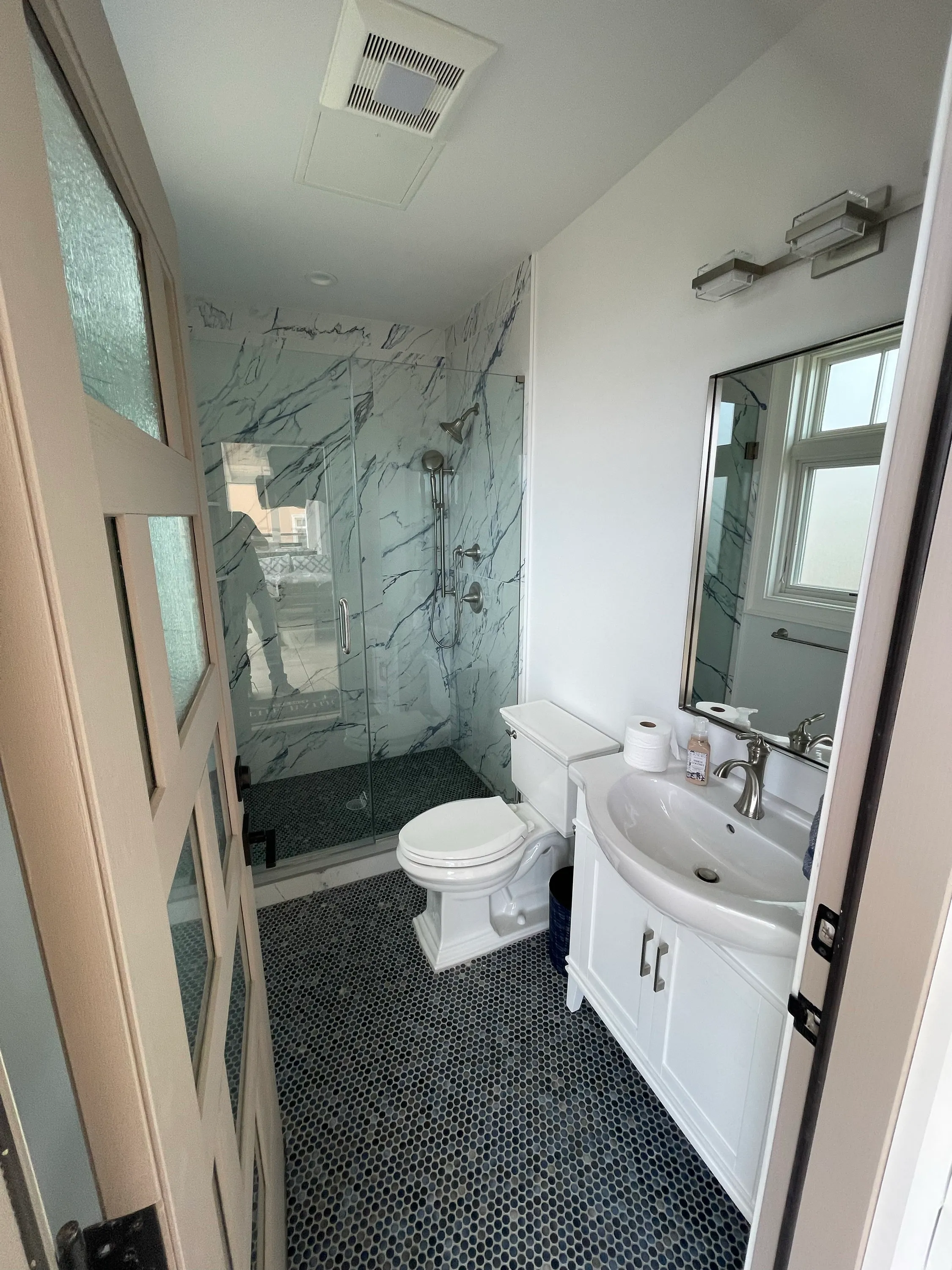 Guest bathroom with stone-patterned tile and a glass shower enclosure.