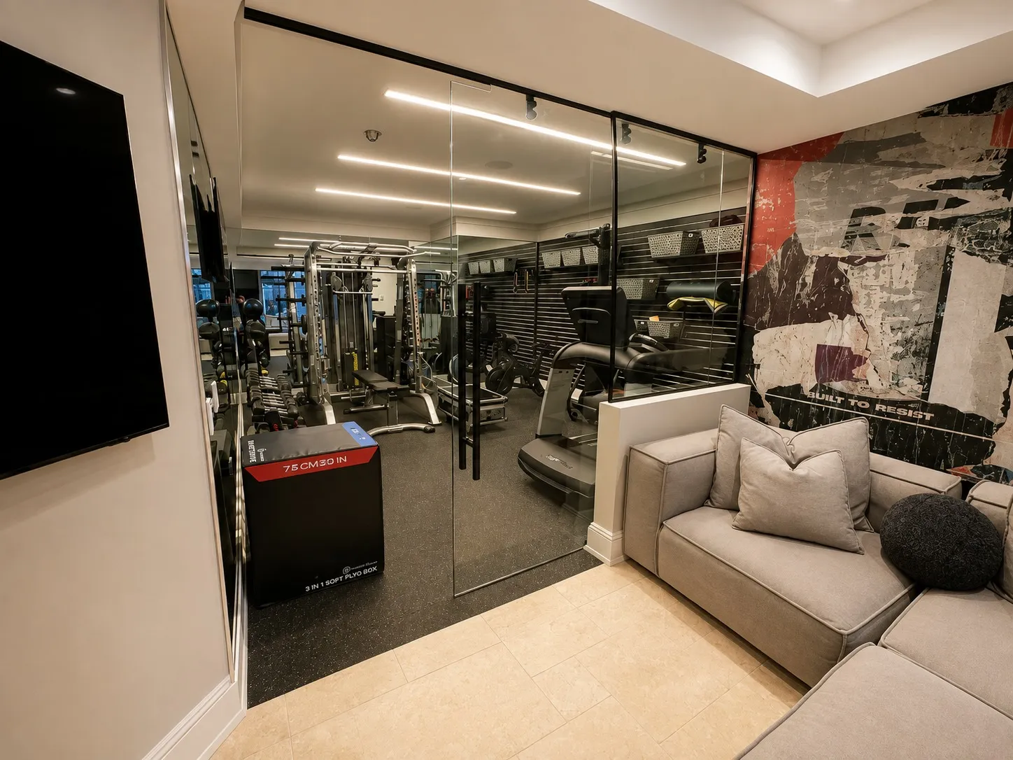 Home gym connected to a sitting area through a full-height glass wall.