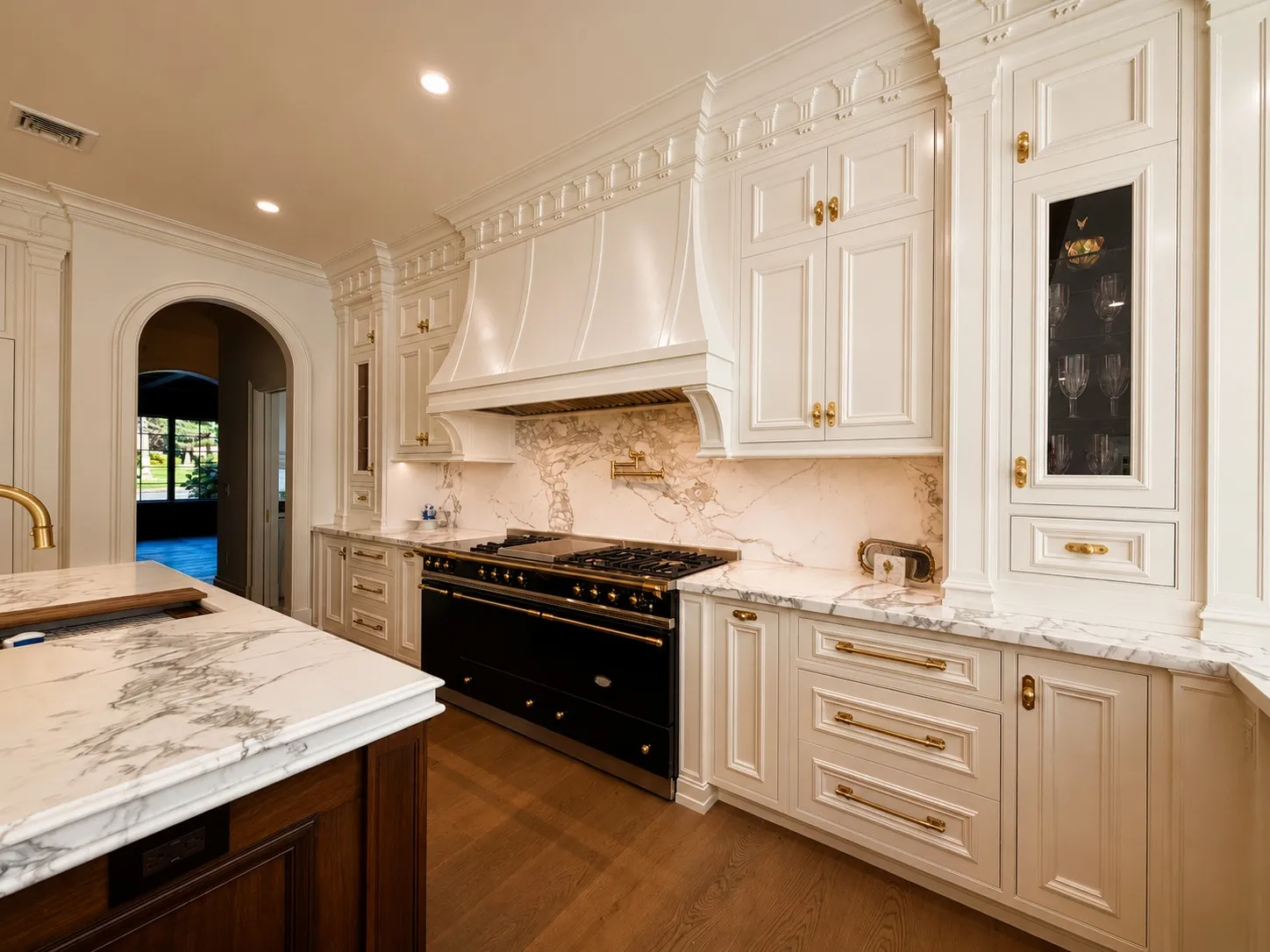 Detailed kitchen millwork surrounding a dark range and marble counters.