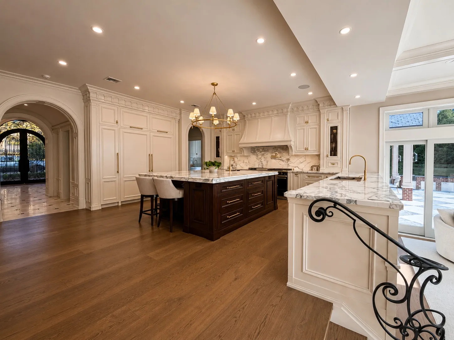 Large kitchen with white millwork, dark wood islands, and marble counters.