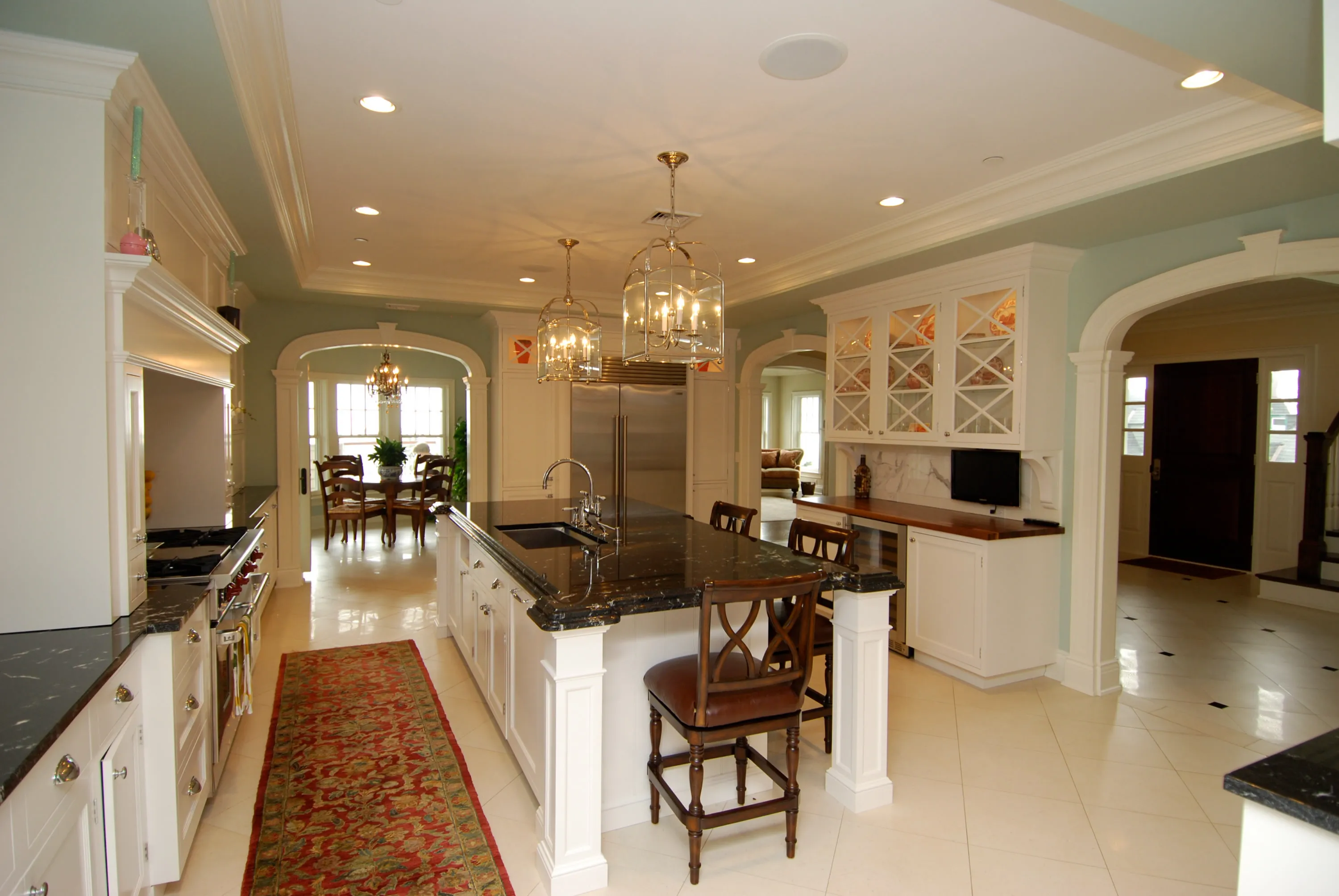 Kitchen with a dark wood island, pale cabinetry, and an open dining connection.