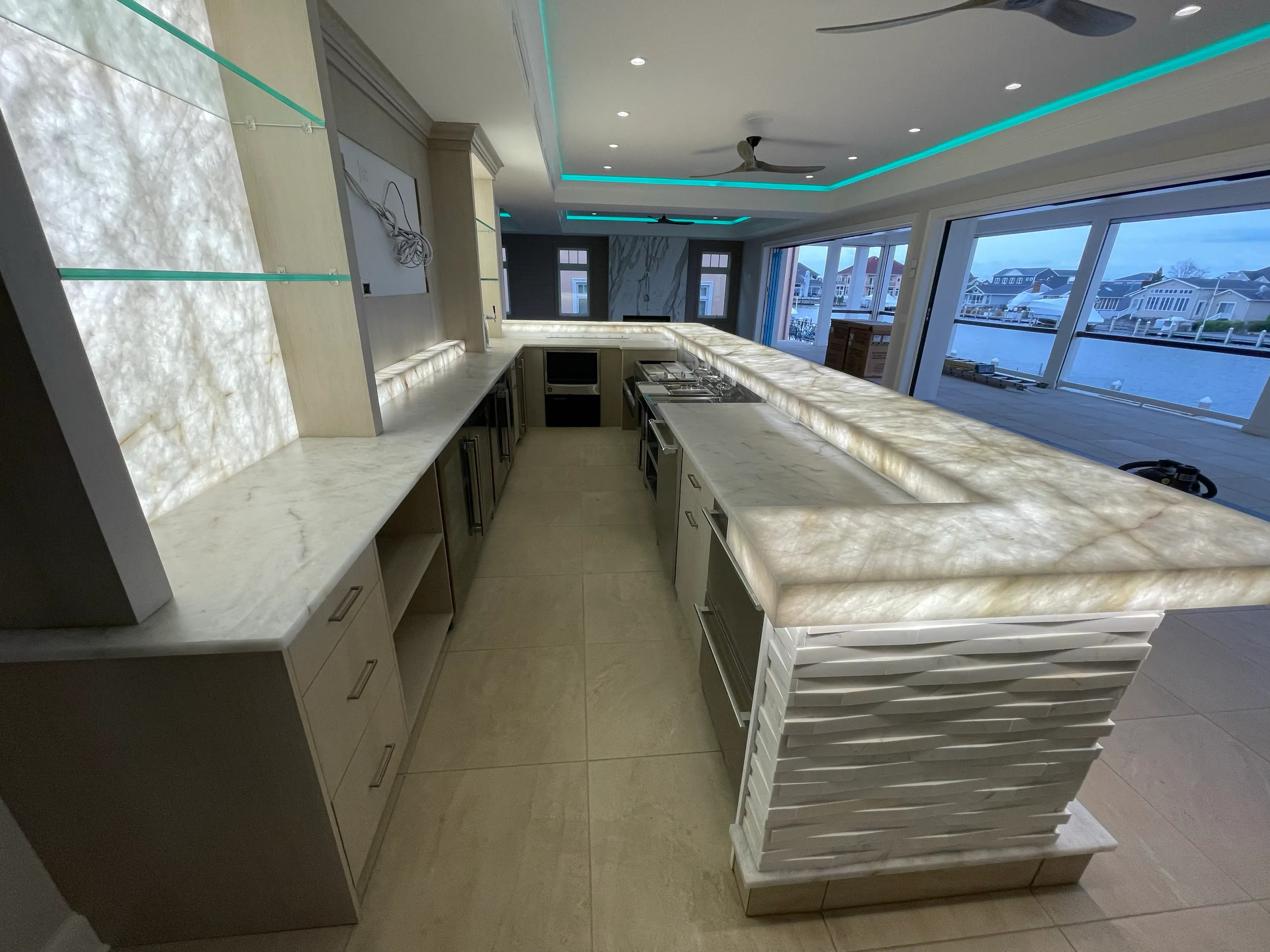 Waterfront kitchen with illuminated stone counters and integrated cabinetry.