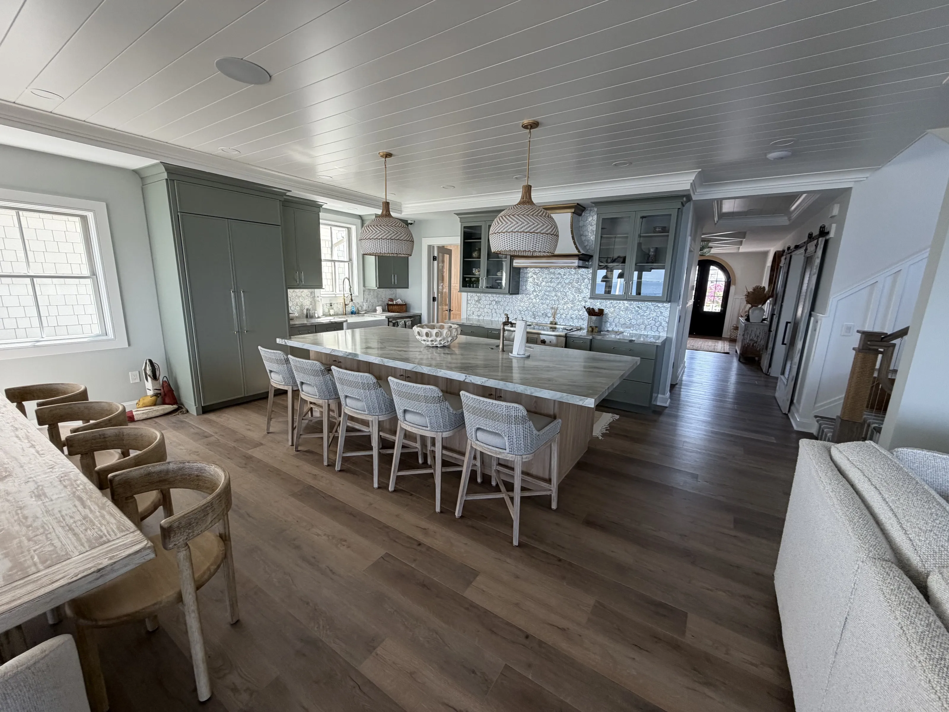 Open coastal kitchen with a large island, pale cabinetry, and wood flooring.