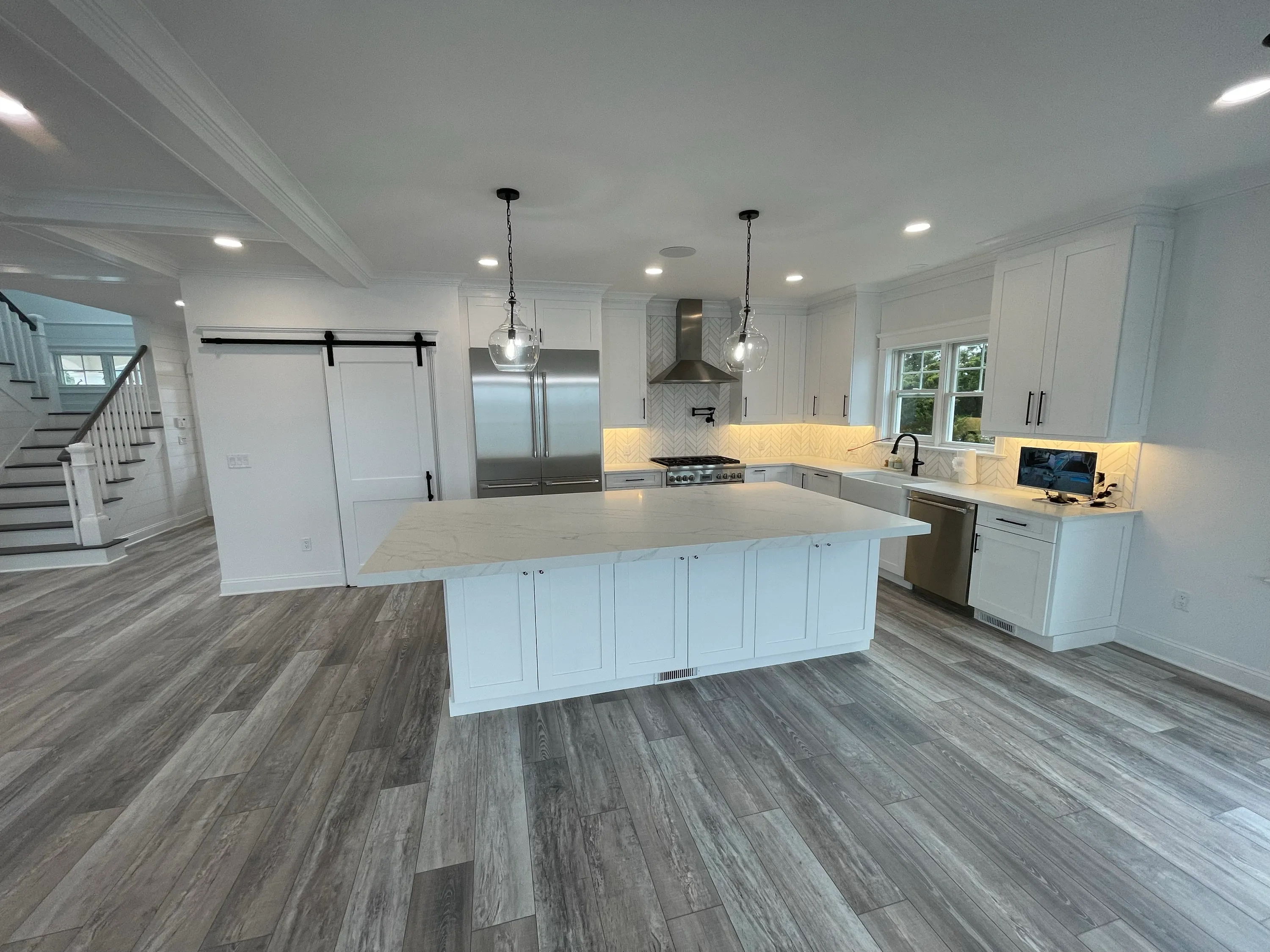 Open kitchen with a broad island, white cabinetry, and detailed ceiling trim.