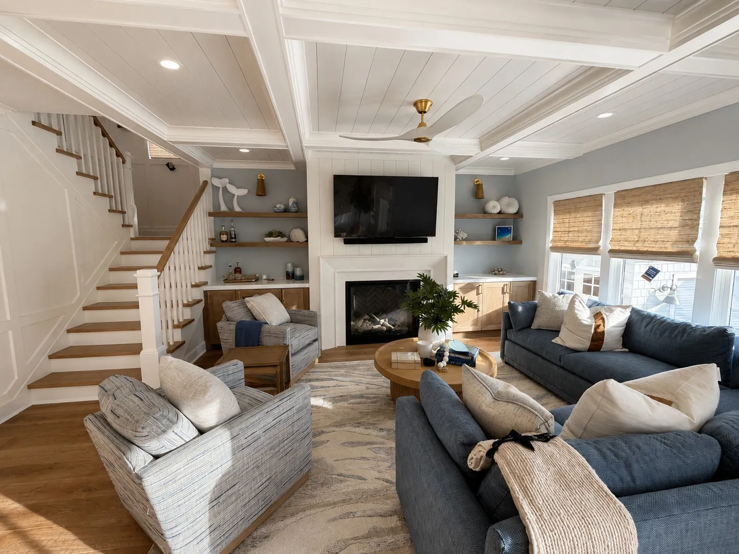 Living room with a fireplace, integrated shelving, and an open stair.