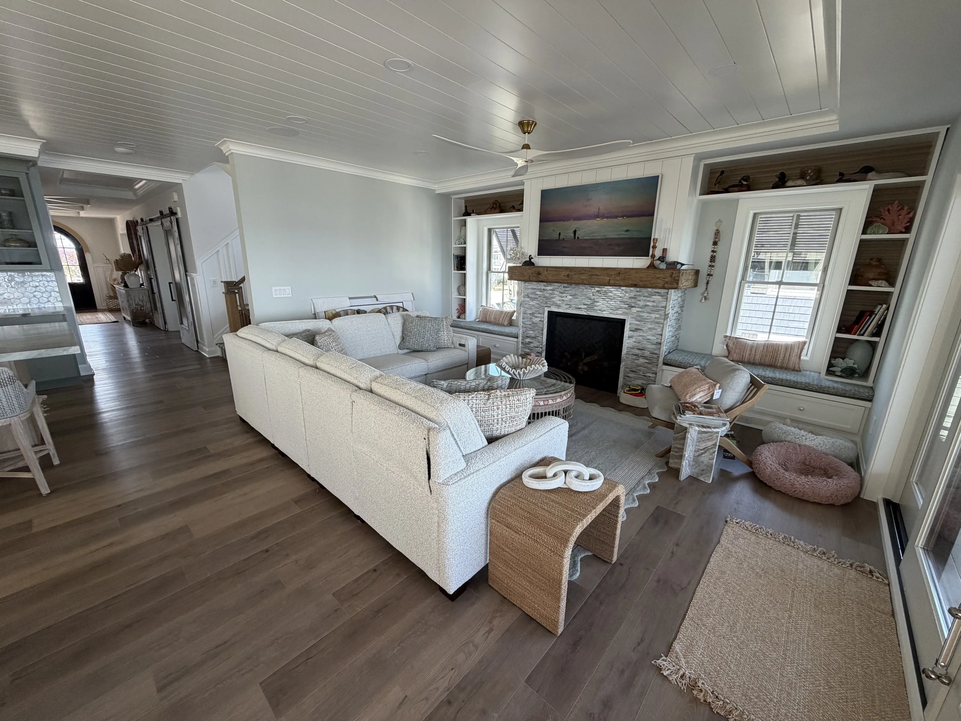 Open living room with built-in shelving, a fireplace, and kitchen beyond.