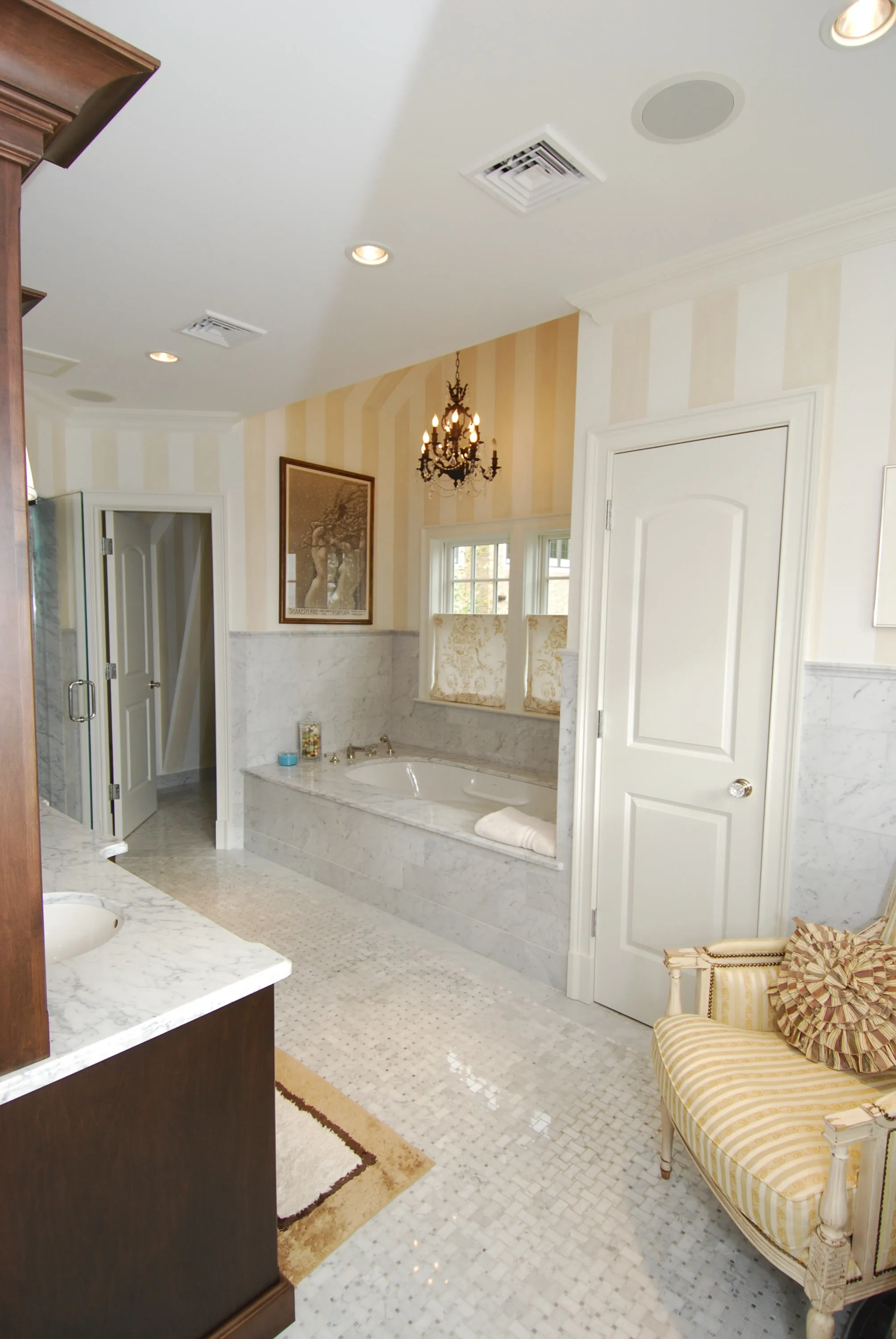 Primary bathroom with a marble tub surround and paneled cabinetry.