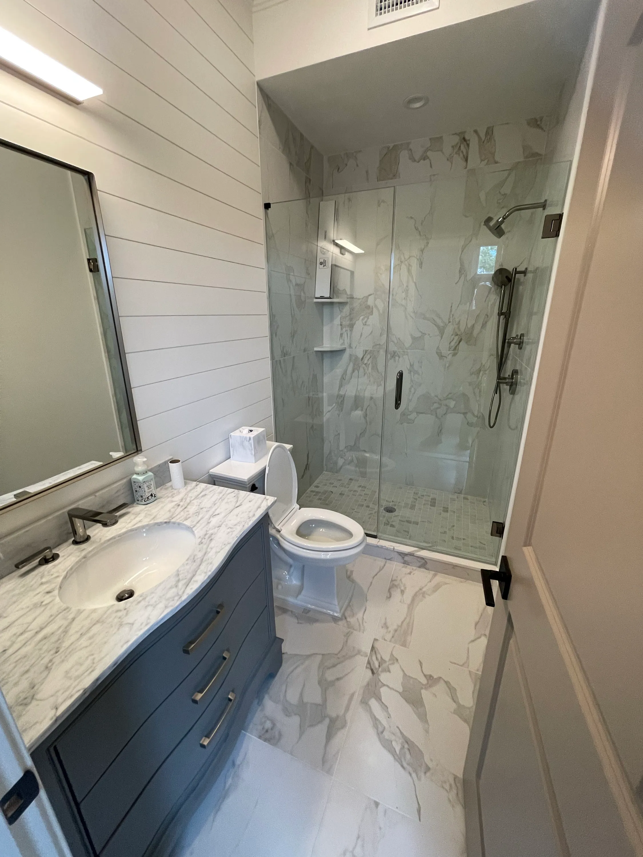 Bathroom with a marble vanity and a glass shower enclosure.