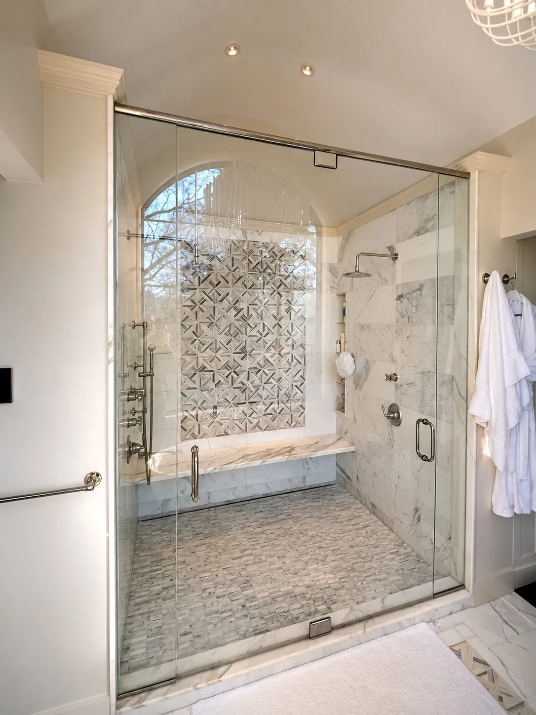 Glass-enclosed shower with stone tile and a curved exterior window.