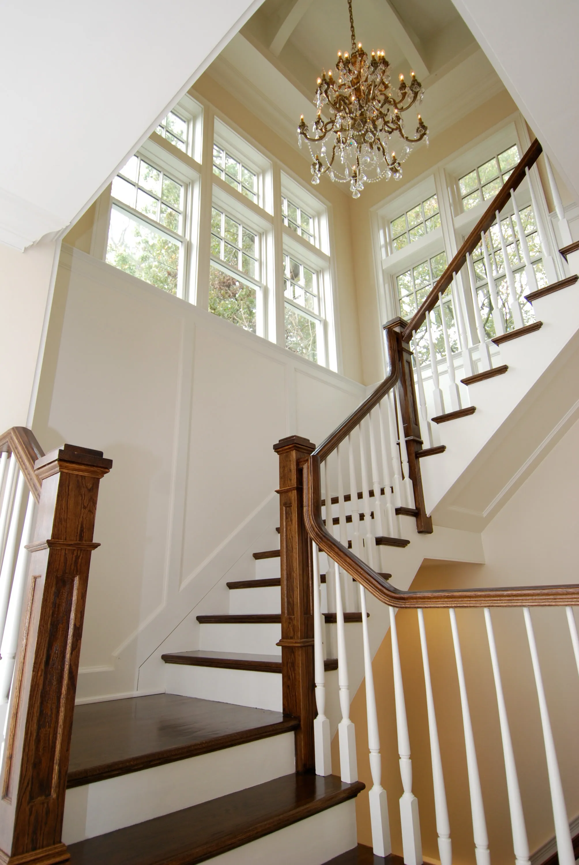 Wood staircase with paneled newel posts and tall windows.