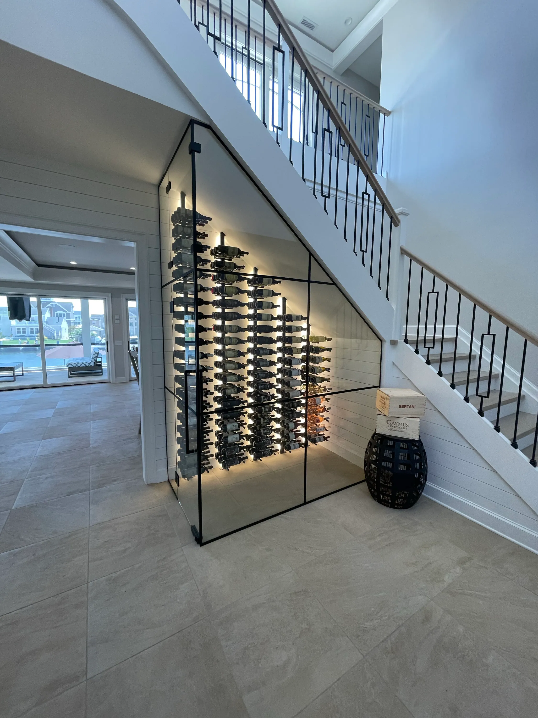 Open stair with custom glass-enclosed wine storage beneath it.