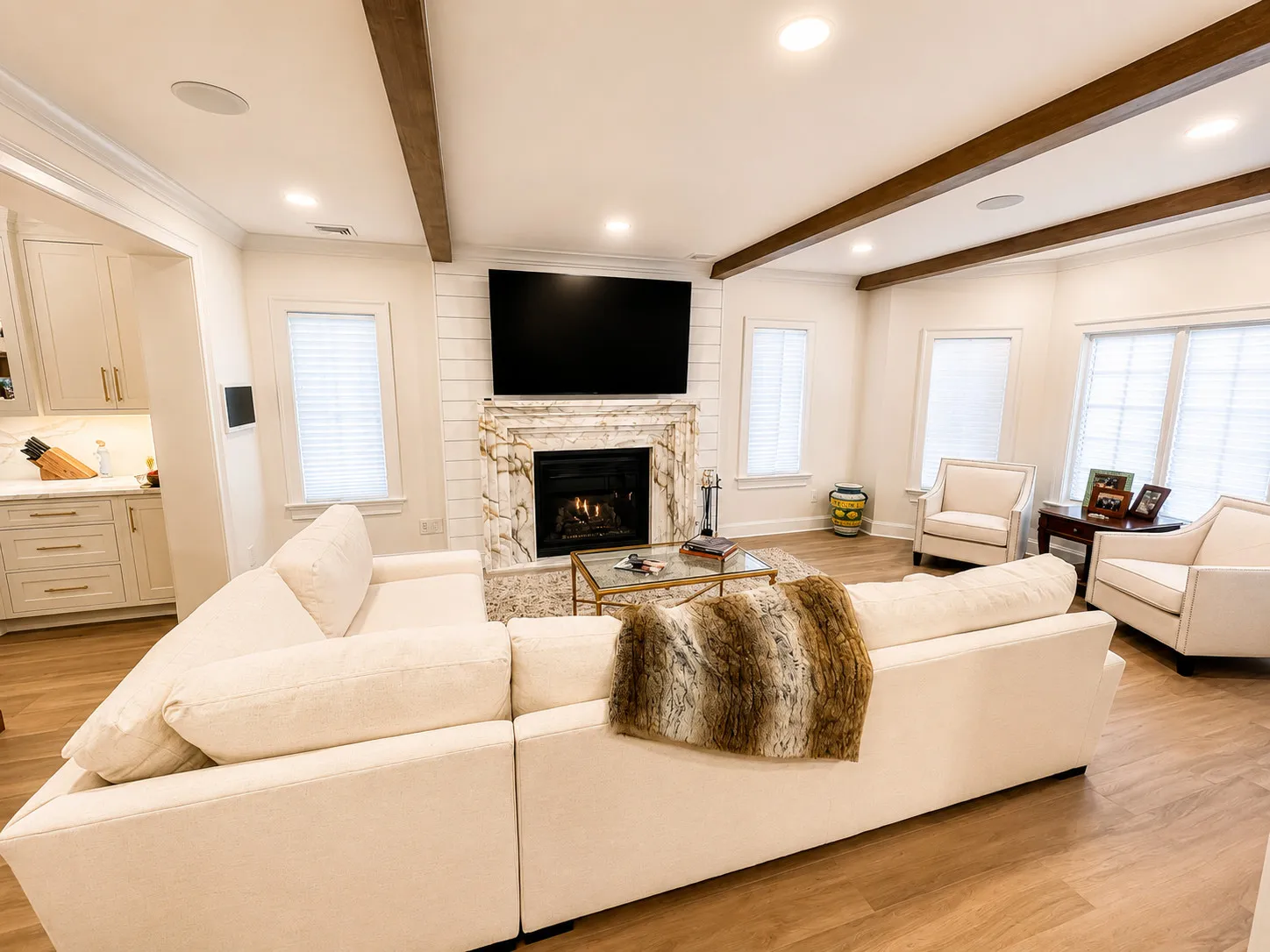 Bright living room with timber ceiling beams and a stone fireplace.