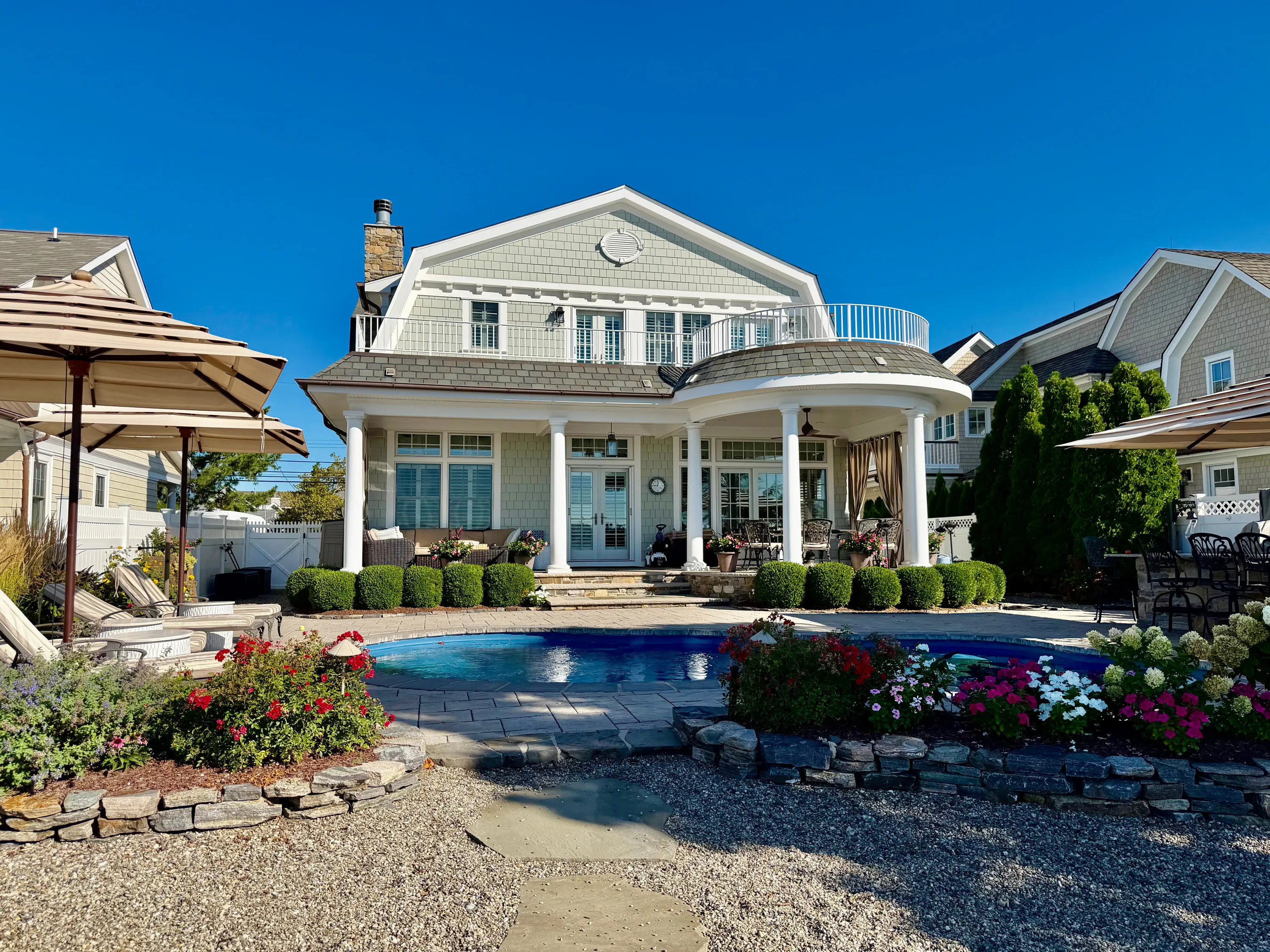 Rear pool and garden framed by flowering landscaping in New Jersey.