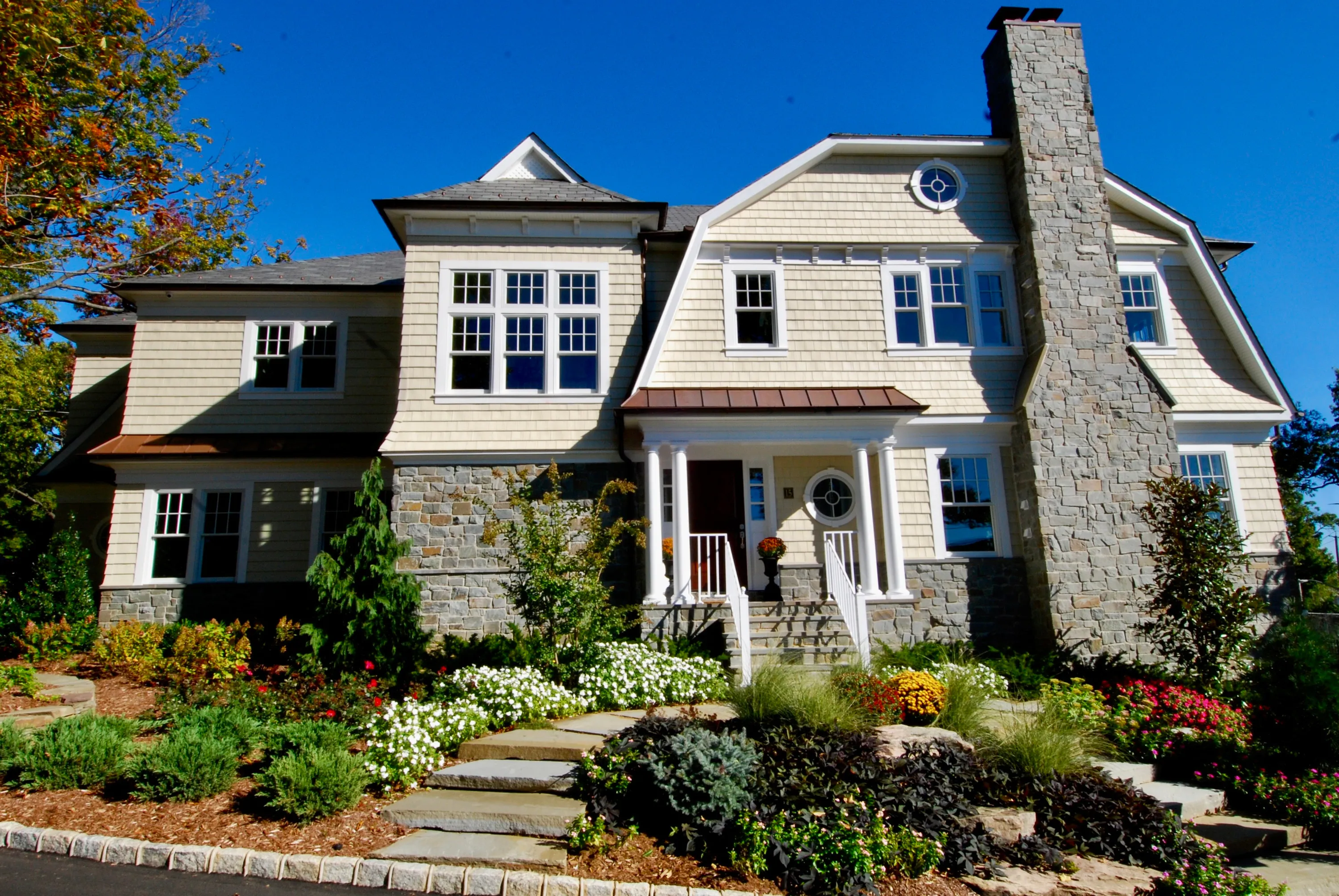 Shingle and stone residence surrounded by mature planting in New York.