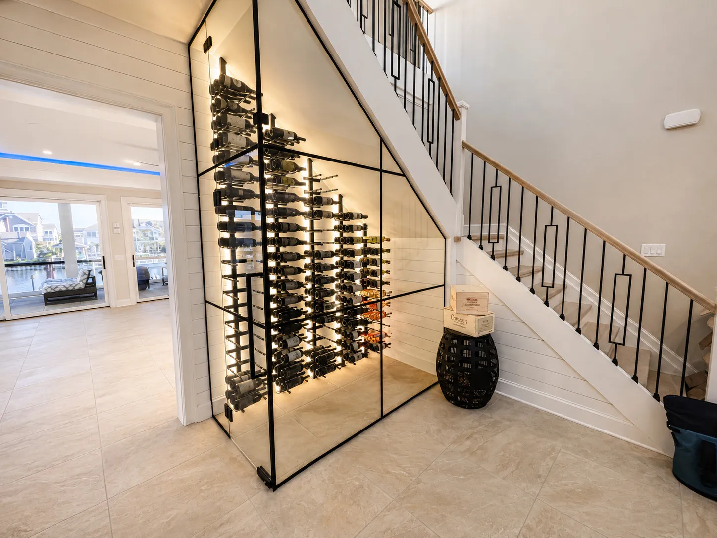 Glass wine display integrated beneath an open staircase.