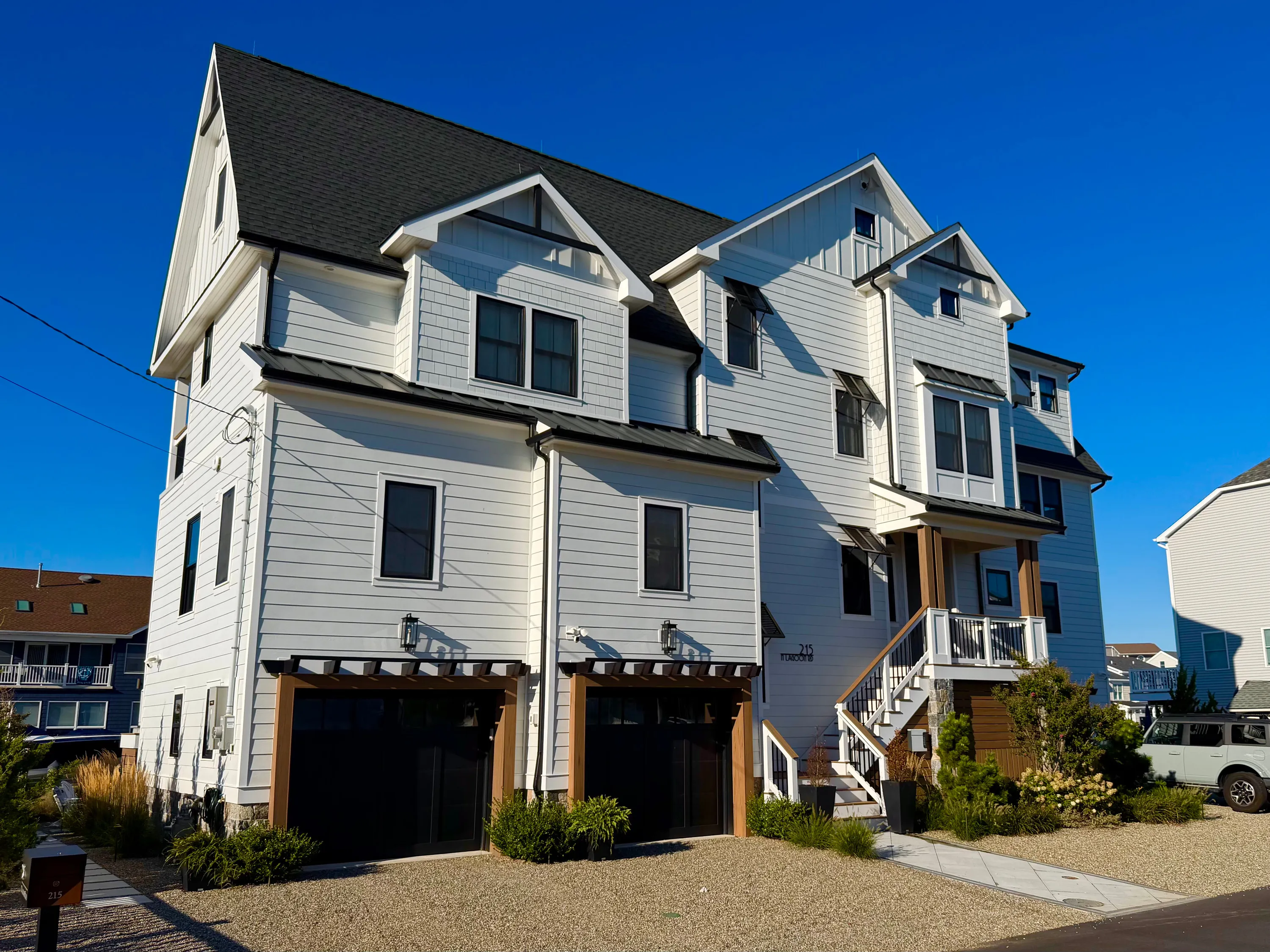 White coastal residence with tall gables and a raised entry in New Jersey.